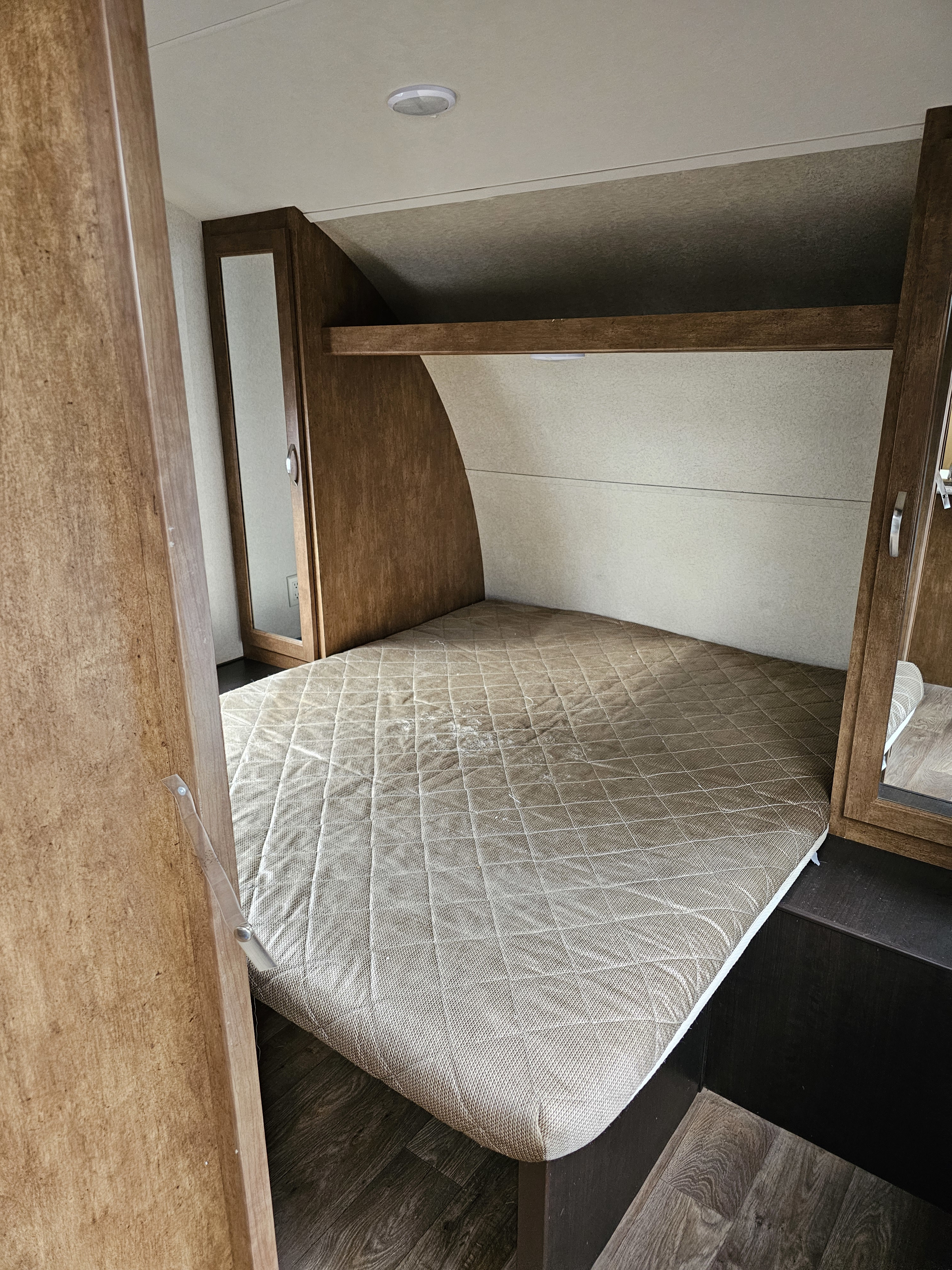 Spacious RV rental bedroom with a comfortable bed, overhead storage, and mirror, perfect for your next adventure.. Forest River Wildwood X-Lite 2018