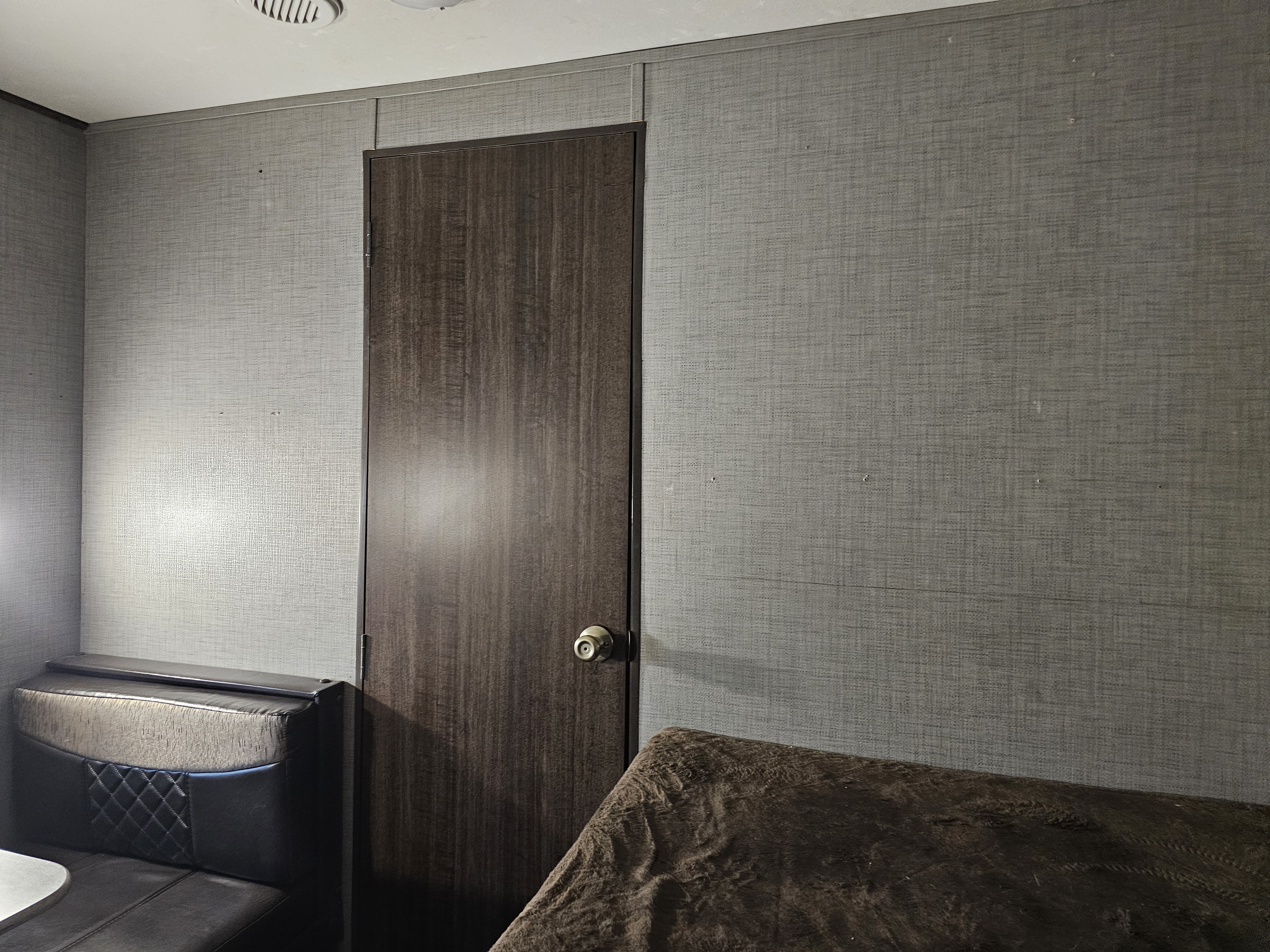 Inside this **rv rental**: textured gray walls, a dark wood door, and a cozy booth seating area. Ready for your next travel adventure!. Keystone Zinger 2018