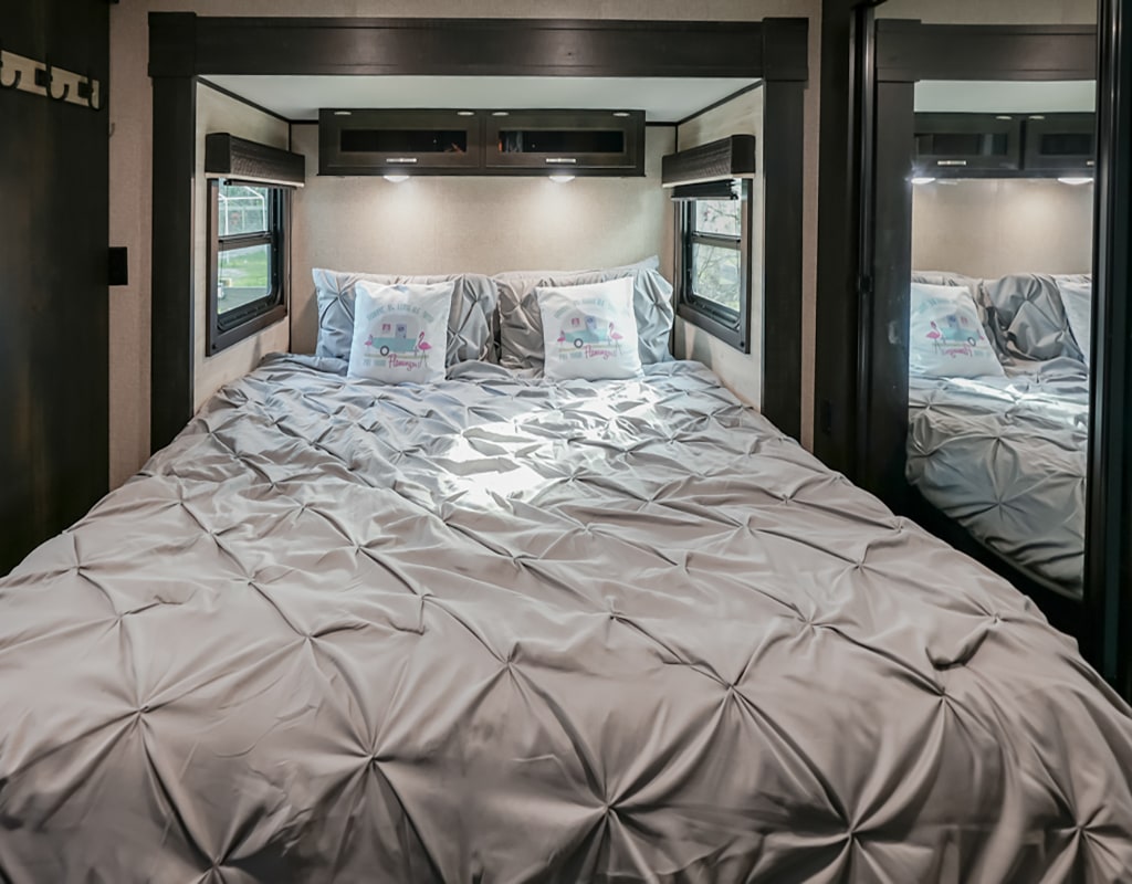 Cozy RV rental bedroom with a large bed, grey pleated bedding, fun camper pillows, and mirrored wardrobe.. Jayco Jayflight 2021