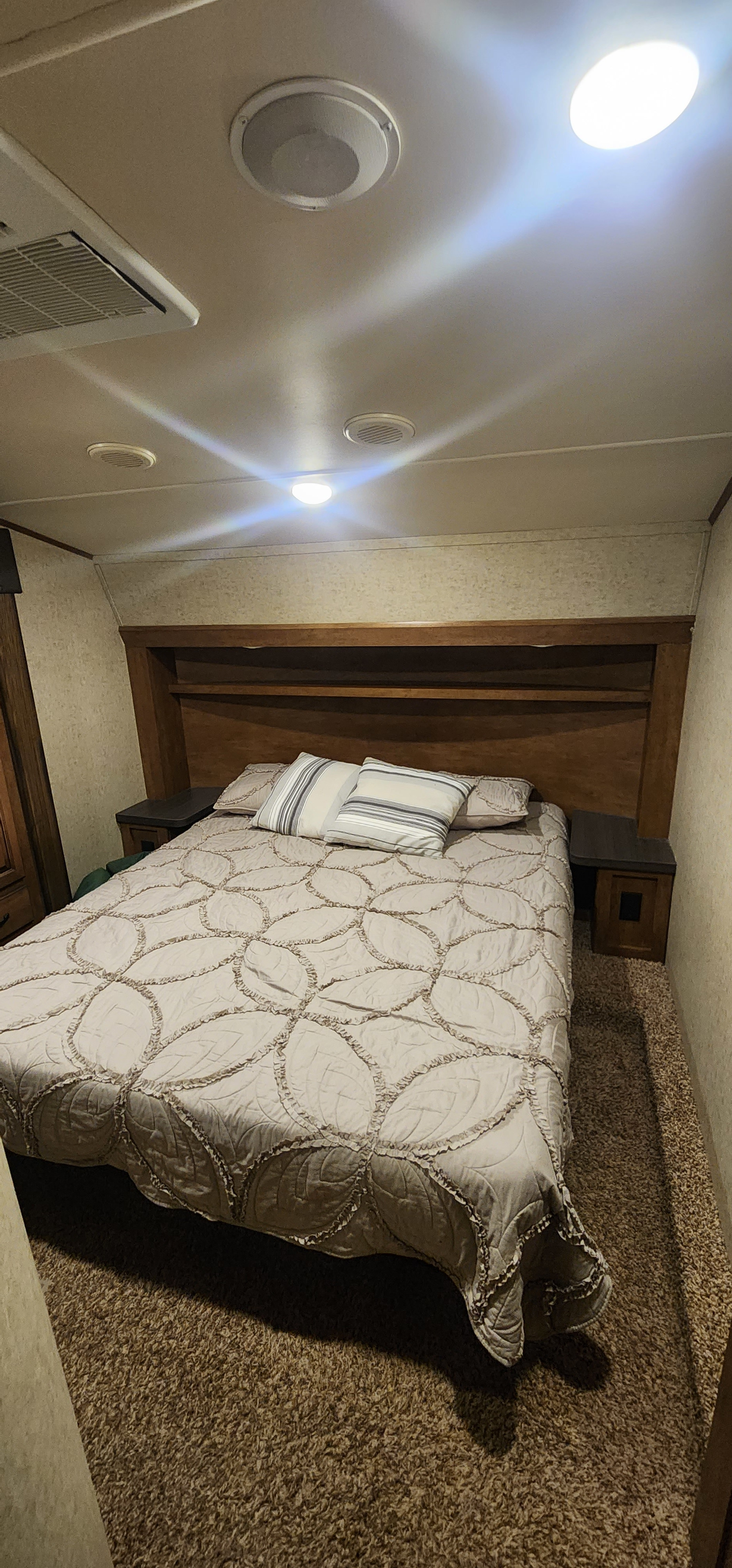 Inside an RV rental, a comfy bedroom features a large bed, wooden headboard with shelves, nightstands, and ceiling fixtures.. Forest River Sabre Sabre Lite 2016