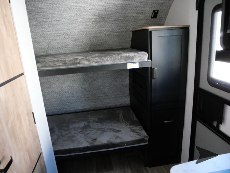 RV rental's cozy interior features bunk beds with grey mattresses and a black storage cabinet. Compact and functional.. Keystone RV Outback Ultra-Lite 2022