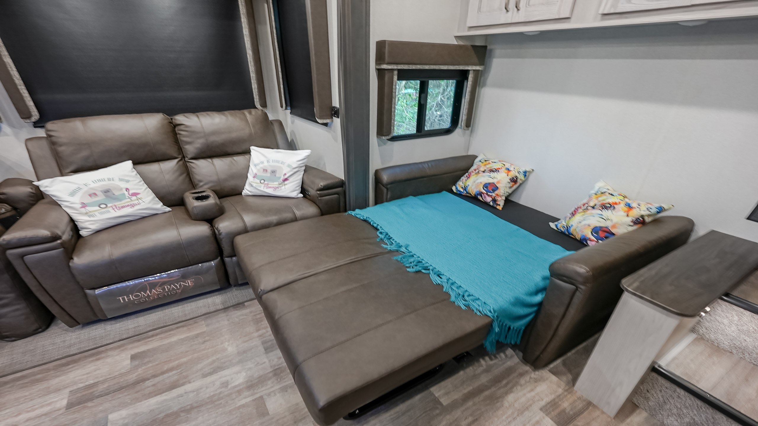 Step into comfort in this RV rental! Plush reclining sofa converts to a cozy bed, adorned with vibrant pillows & blue blanket.. Keystone Montana High Country 2021