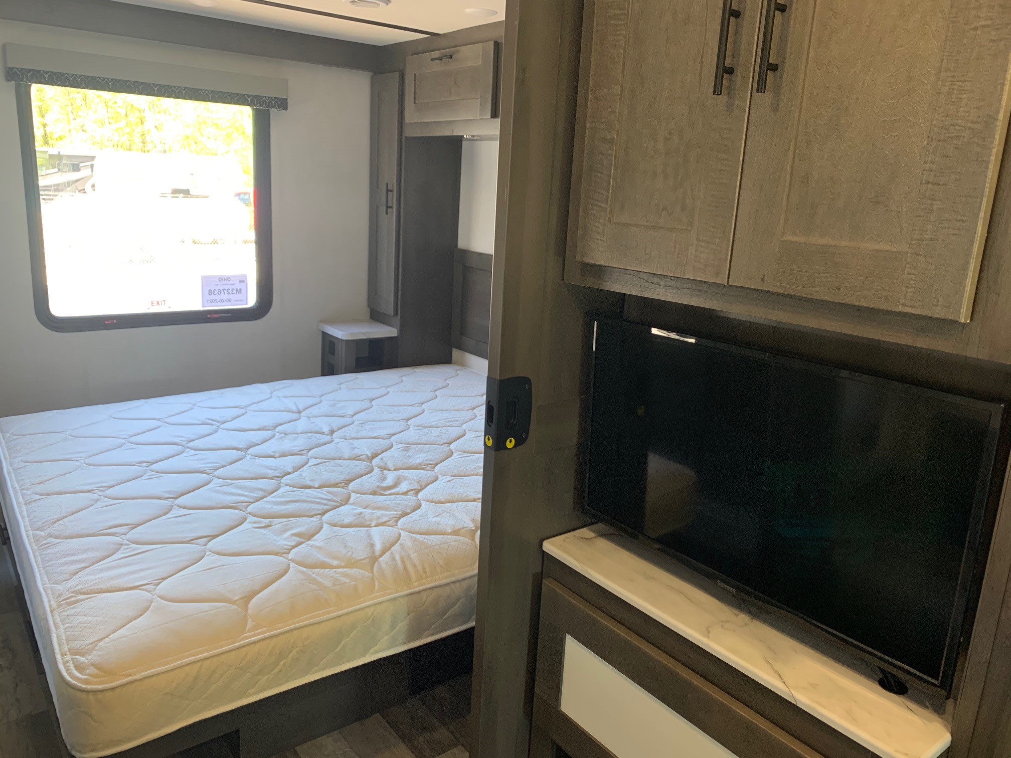 Spacious RV rental bedroom featuring a comfortable bed, window, TV, and ample storage cabinets.. Forest River Fr3 2025