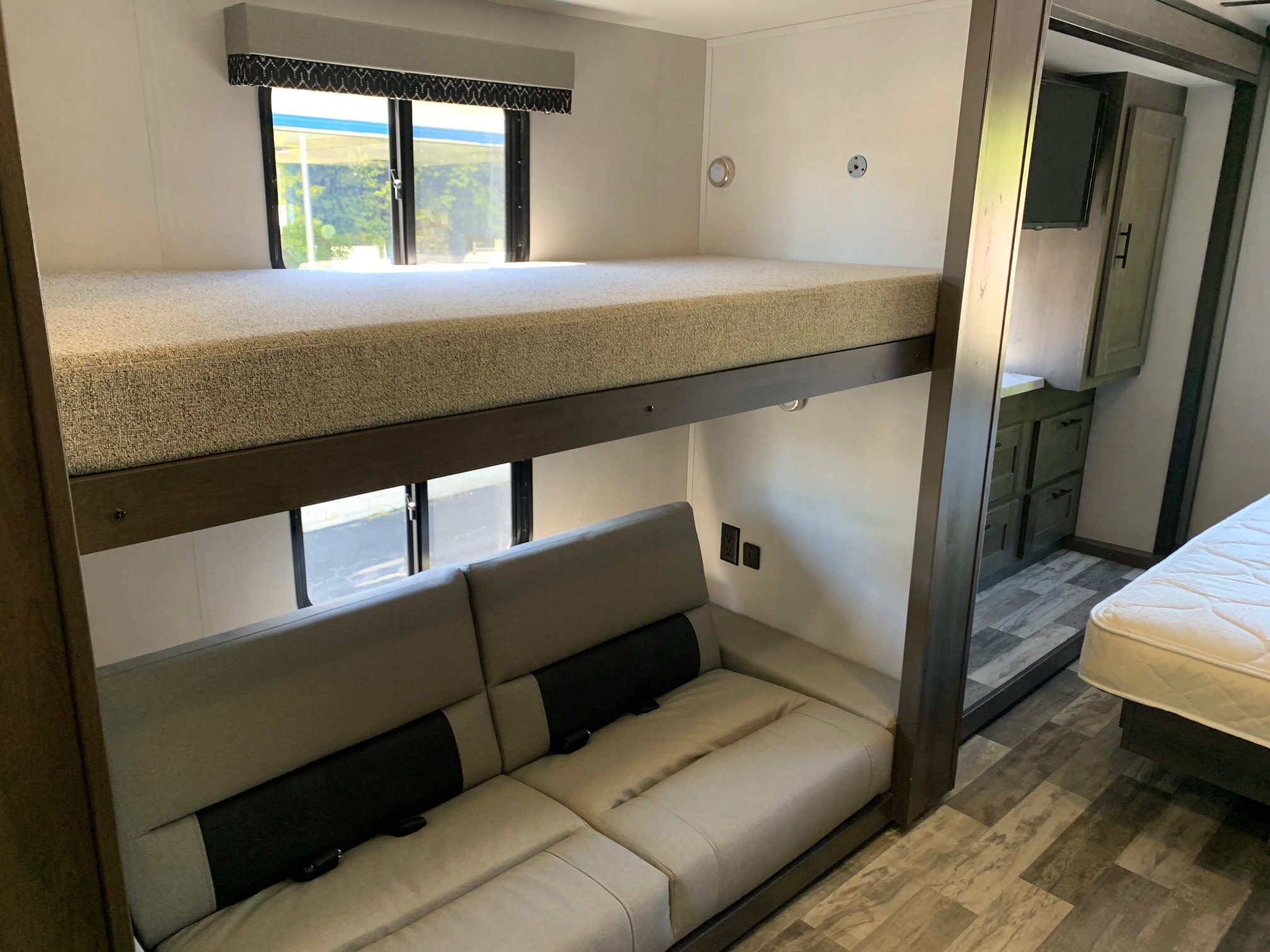 This RV rental interior features versatile bunk beds, a sofa, and a bedroom area, perfect for family comfort.. Forest River Fr3 2025