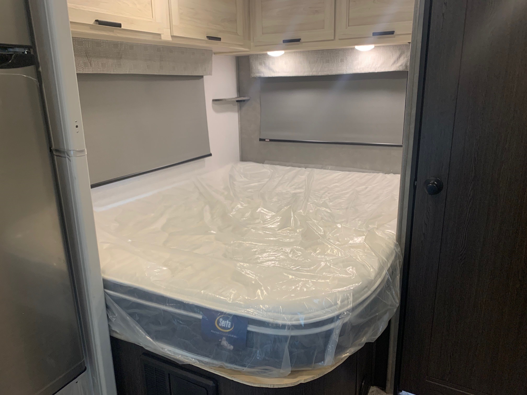 RV rental bedroom with a new Serta mattress in plastic. Features overhead cabinets, blinds, and a cozy interior.. Forest River Sunseeker 2026