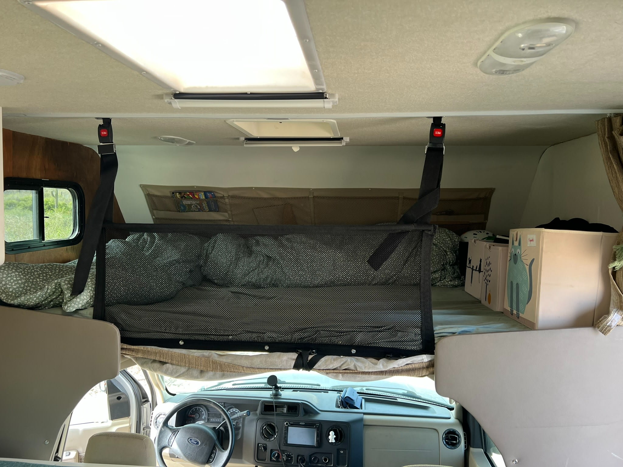 RV rental interior showing a cozy cab-over bunk with a safety net, pillows, and storage bins above the driver's cab.. Adventurer Adventurer Motorhome 2016
