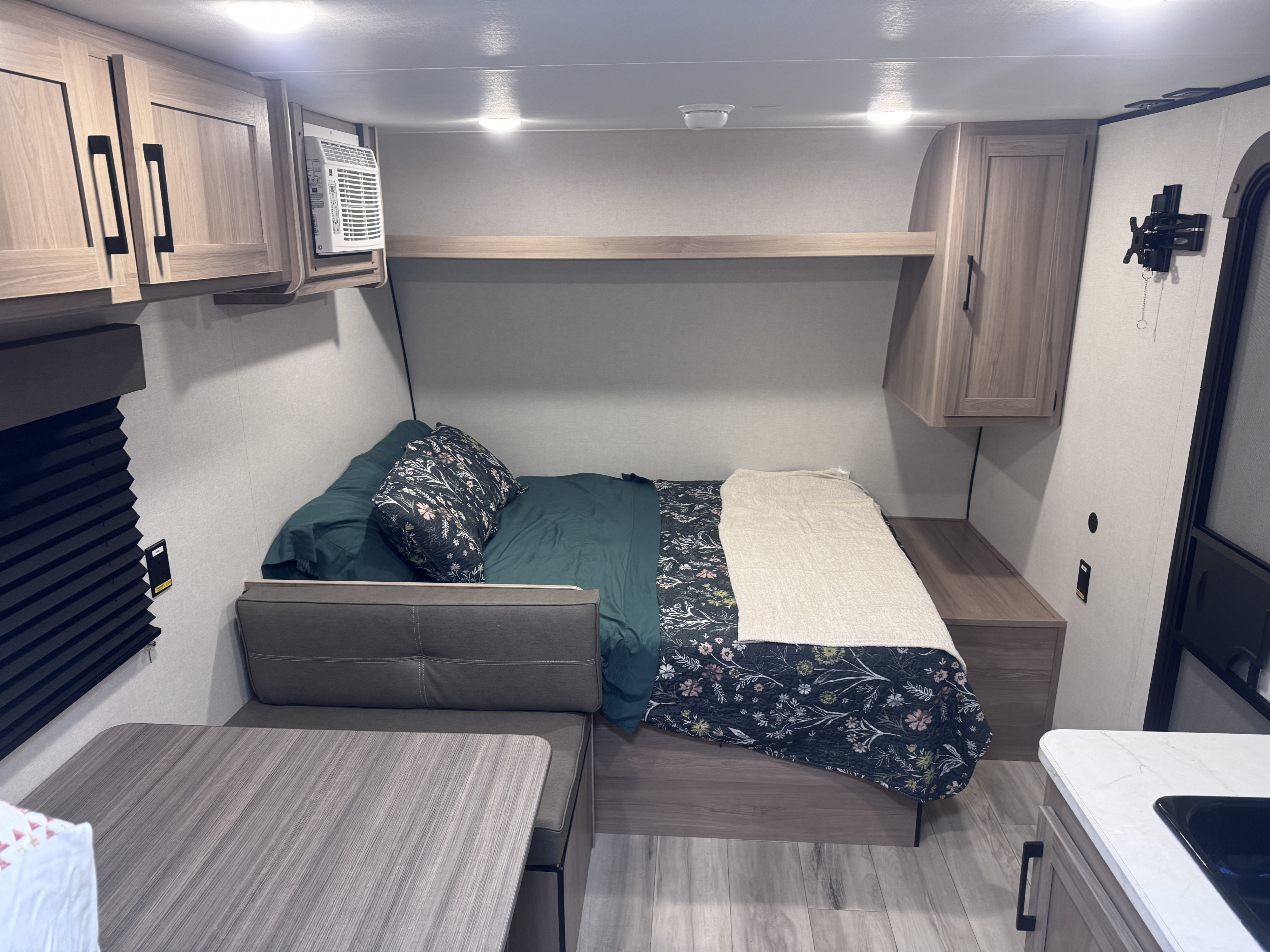 Cozy RV rental interior with a comfortable bed, dinette, overhead cabinets, and a compact kitchenette.. Keystone Coleman 17B 2025