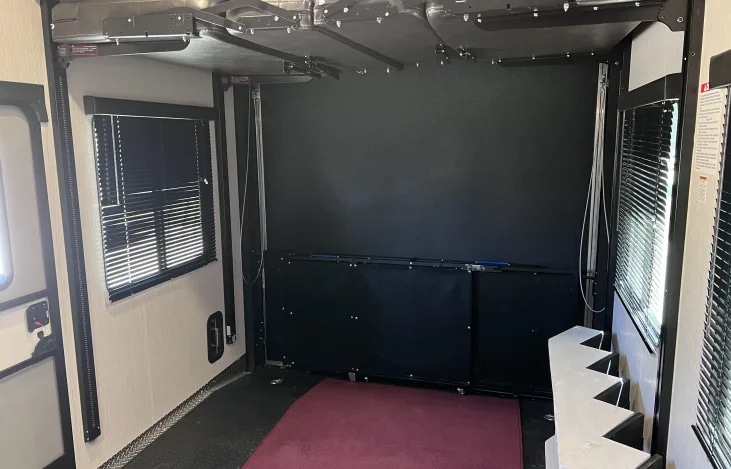 Inside this RV rental, discover a spacious toy hauler garage with a ceiling bed lift system, window blinds, and steps.. Heartland Road Warrior 2021