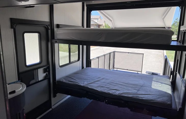 RV rental: Two bunk beds lowered in a toy hauler interior, with an open rear patio view.. Heartland Road Warrior 2021