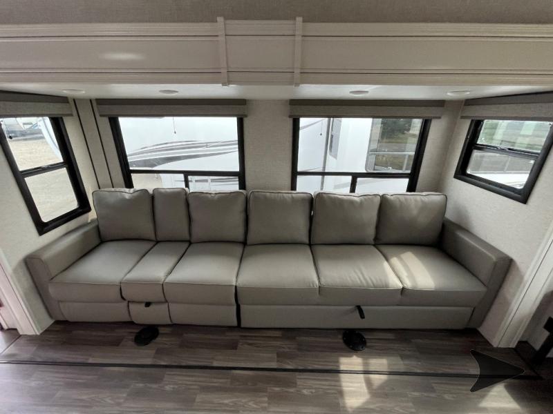 RV rental living room with a long, modular sofa (likely pull-out bed) & multiple windows.. Highland Ridge RV Open Range Roamer 2024