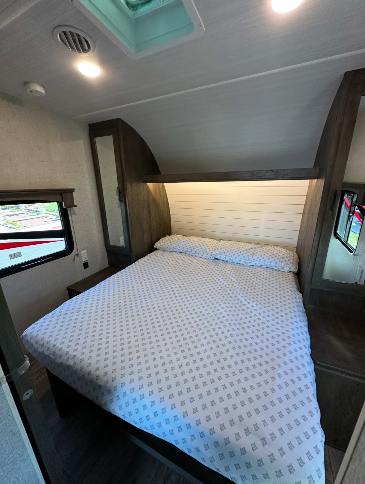 RV rental bedroom: a cozy space with a comfortable bed, illuminated headboard, and skylight.. Forest River Shockwave 2021