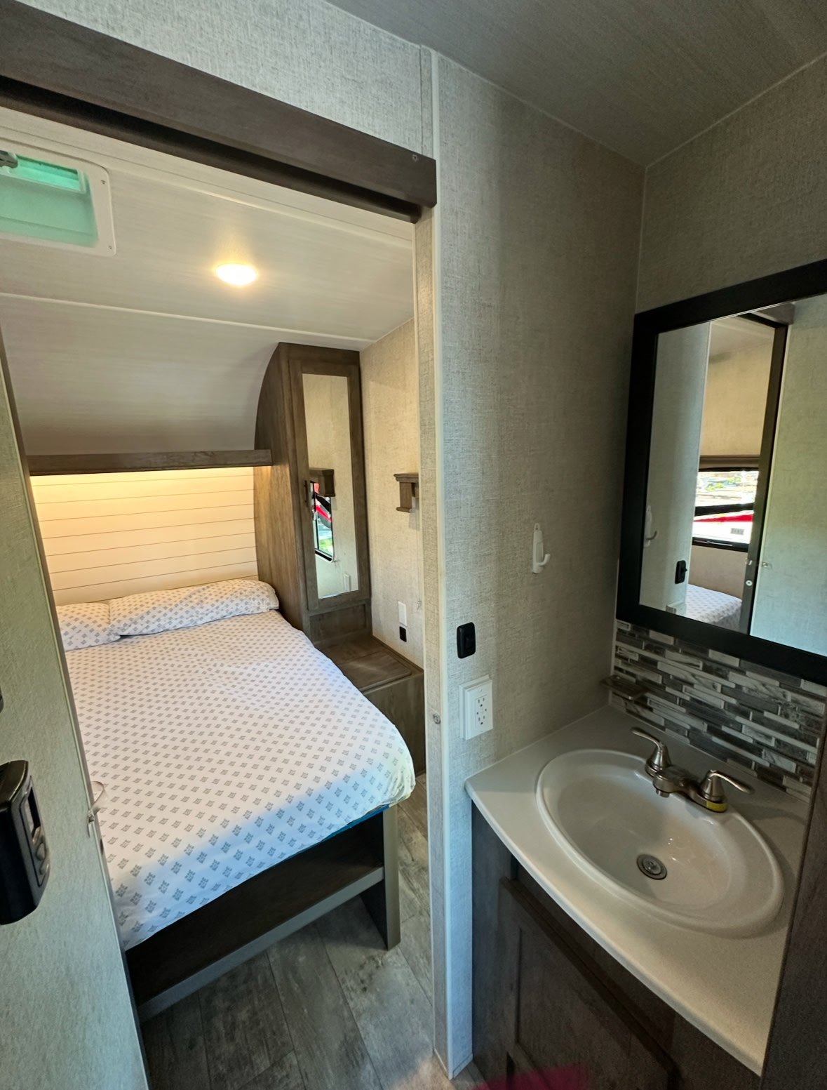 Explore this RV rental's inviting bedroom and practical bathroom, designed for comfortable travel trailer trips.. Forest River Shockwave 2021