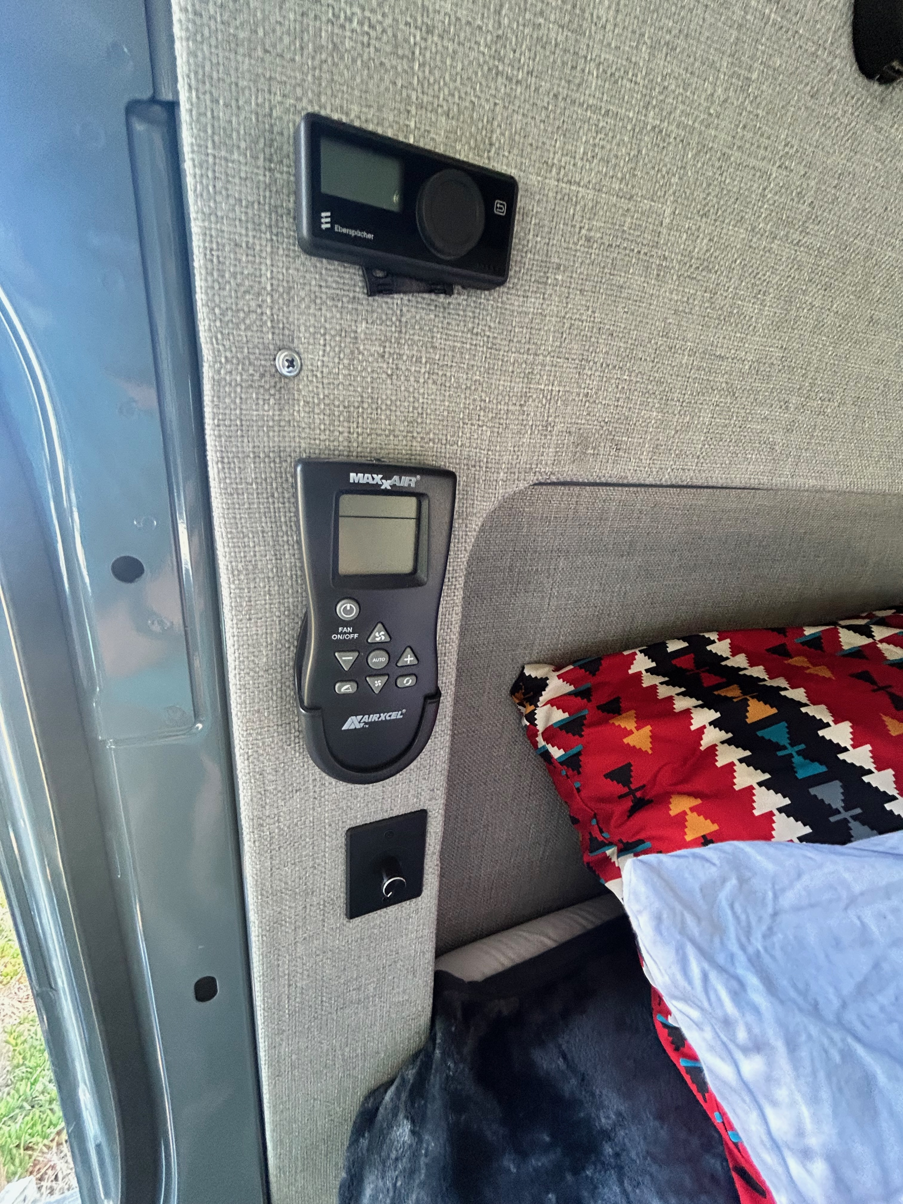 RV rental interior showing Eberspächer heater & MaxxAir fan controls, next to a bed with a colorful pillow.. Mercedes-Benz Sprinter 144 2023