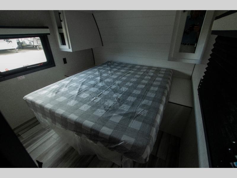 Cozy RV rental bedroom featuring a checkered bed, window view, and smart storage. Perfect for compact living on the go.. Jayco Jay Flight 2024