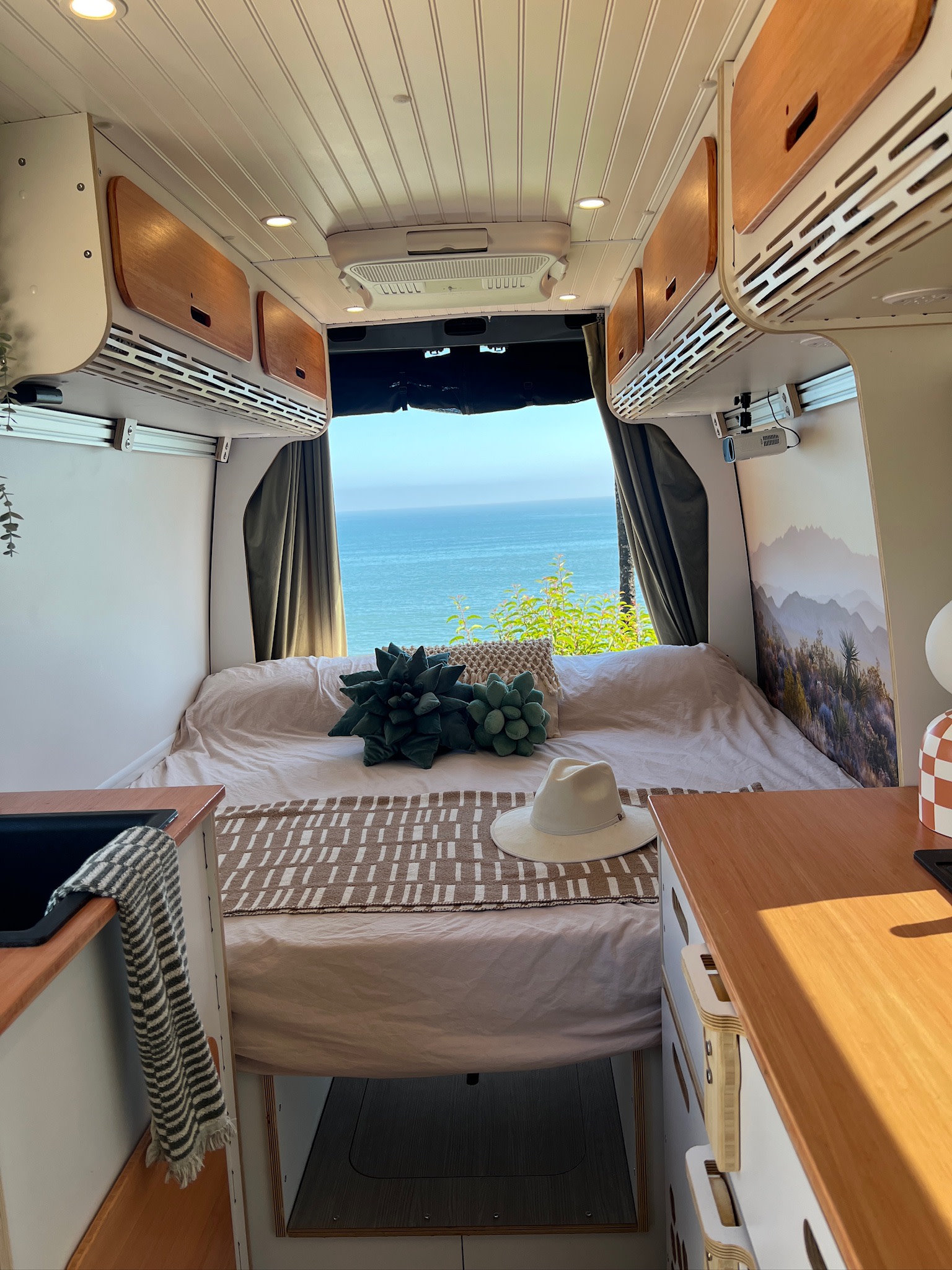 Experience van life in this RV rental: a custom interior featuring an ocean-view bed, projector, and kitchen.. Mercedes-Benz Sprinter 2022