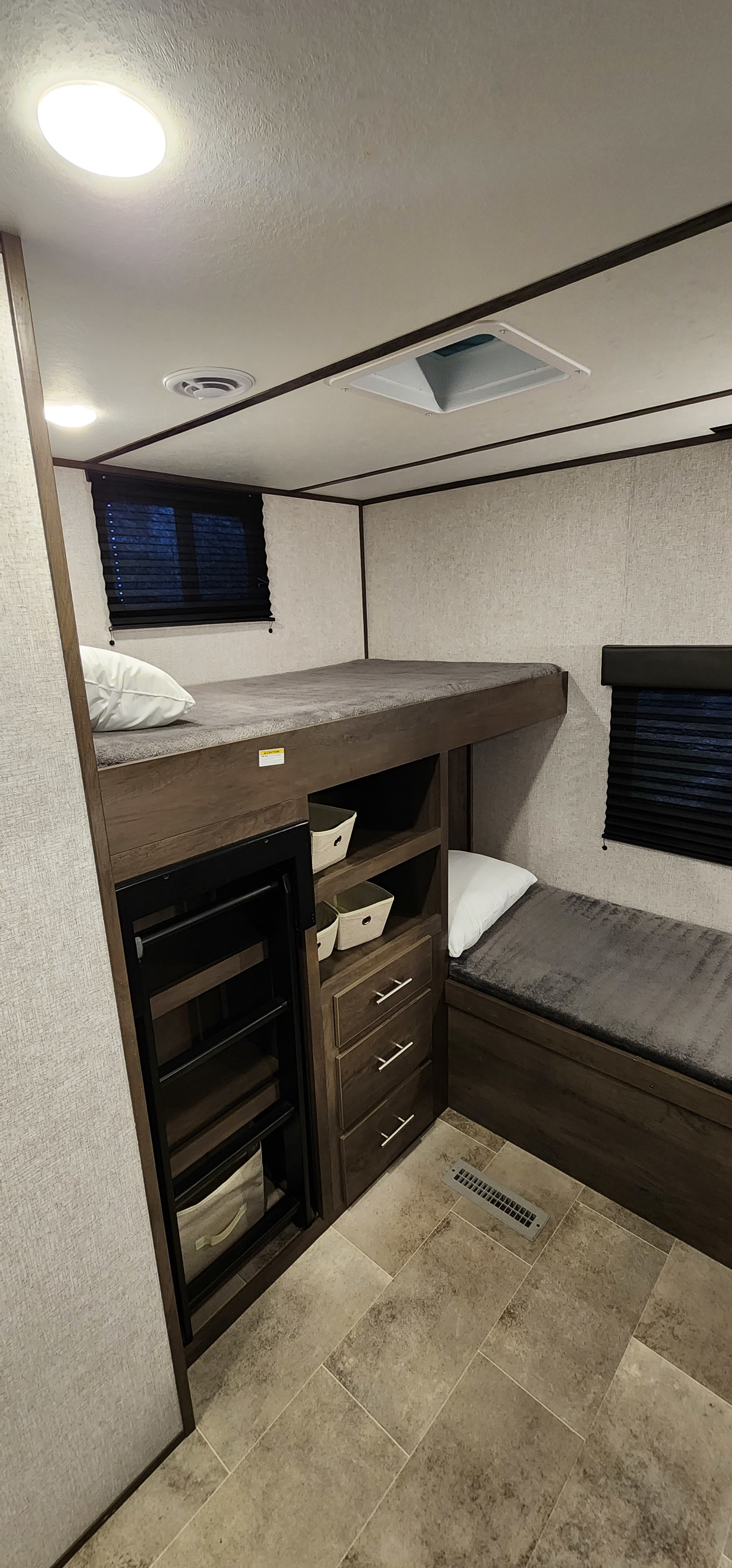RV rental: bunk beds, lower bench, storage, and small fridge in a compact, functional interior space.. Dutchmen Coleman Lantern 2021