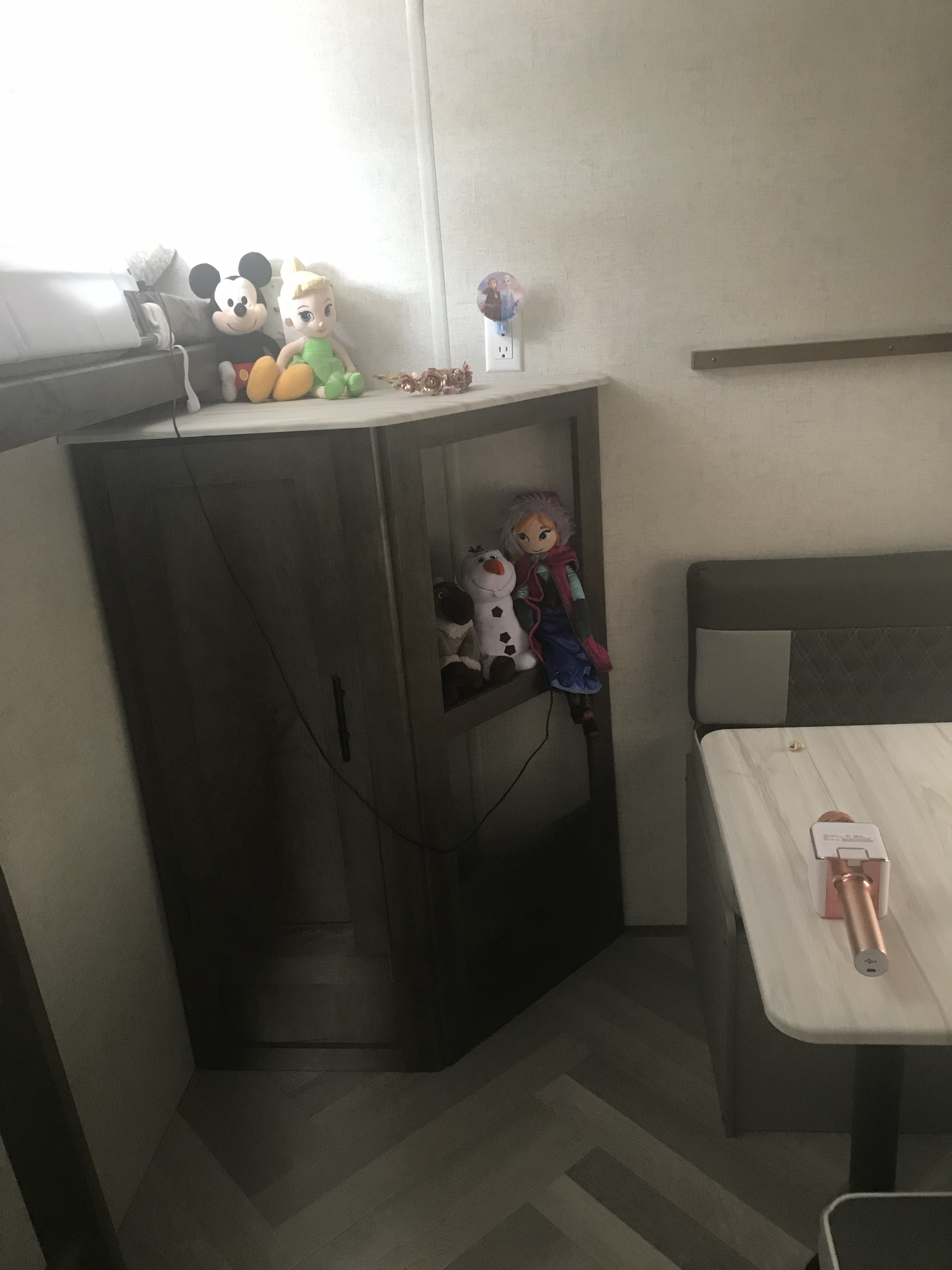 RV rental interior: Mickey Mouse, Tinkerbell, Olaf, and Anna dolls on a cabinet, plus a table with a mic for family fun.. Forest River Wildwood 2021