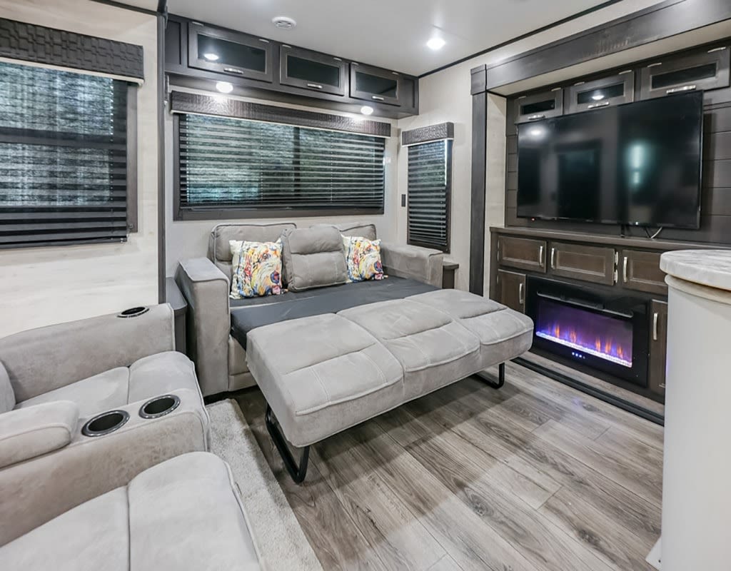 Spacious RV rental living area with sofa bed, recliner, TV, and fireplace for ultimate comfort.. Jayco Jayflight 2021