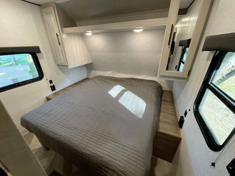 Spacious RV rental bedroom featuring a gray bed, overhead cabinets, and large windows. Ideal for comfortable travel.. Crossroads RV Funtime 333sk 2024