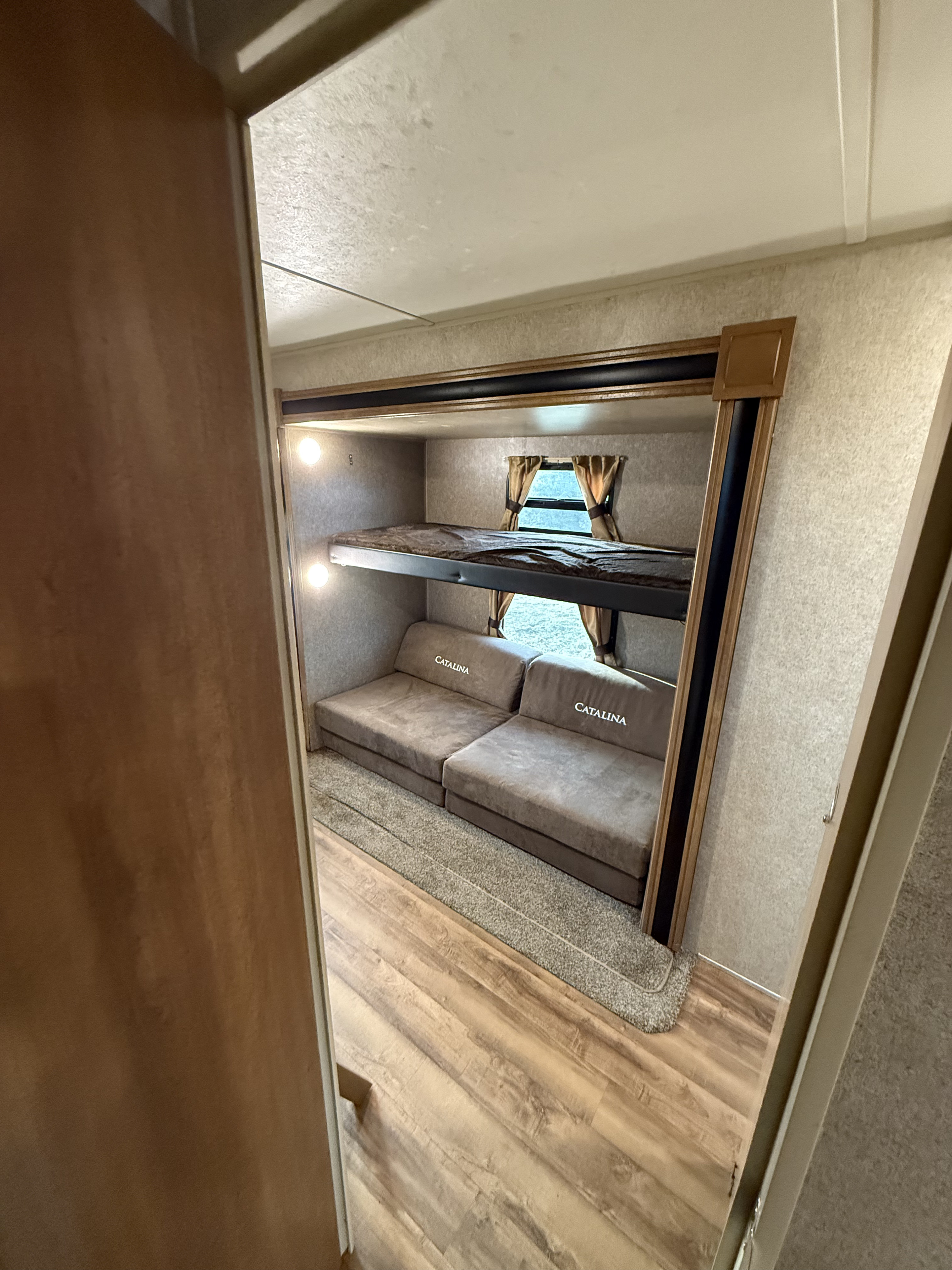 RV rental interior: two bunk beds above convertible 'CATALINA' sofa beds, with windows, seen from a doorway.. Forest River Coachmen Catalina Legacy 2018