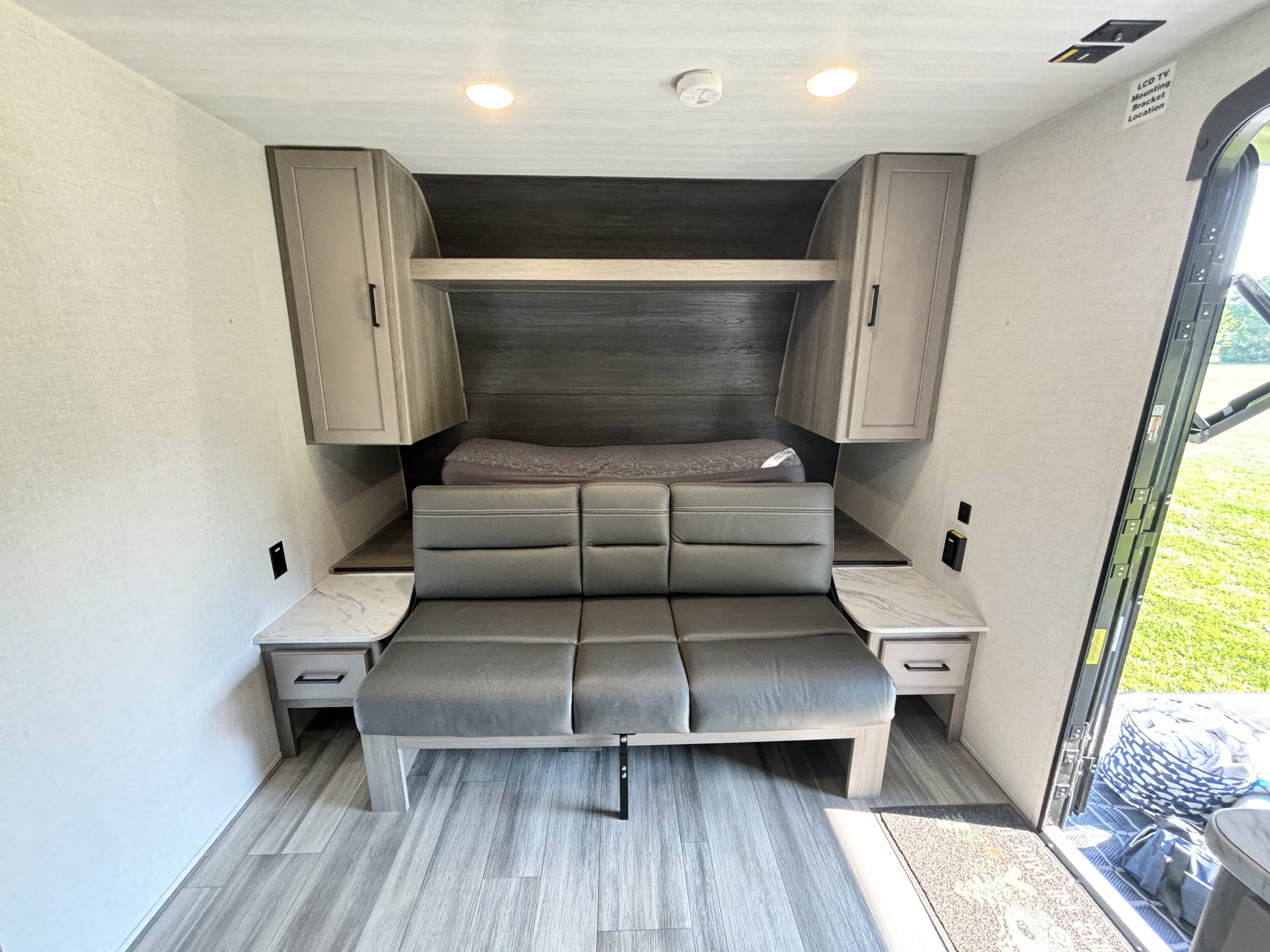 Modern RV rental interior featuring a convertible sofa bed, ample storage, and practical side tables for comfort.. Keystone RV Hideout 181BH 2024