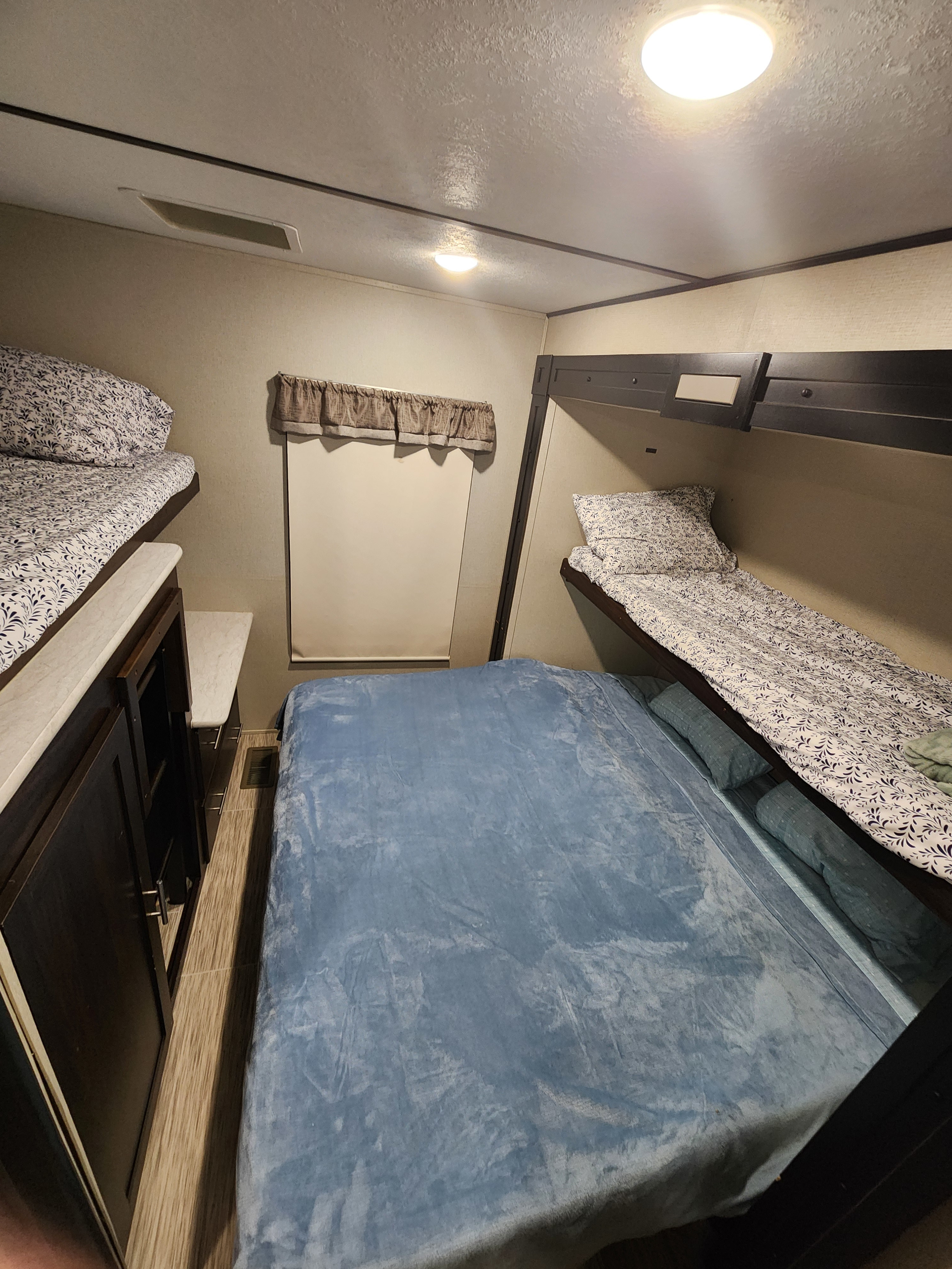 This rv rental interior features a spacious bedroom with bunk beds, a main bed, and built-in storage.. Prime Time Lacrosse 2019