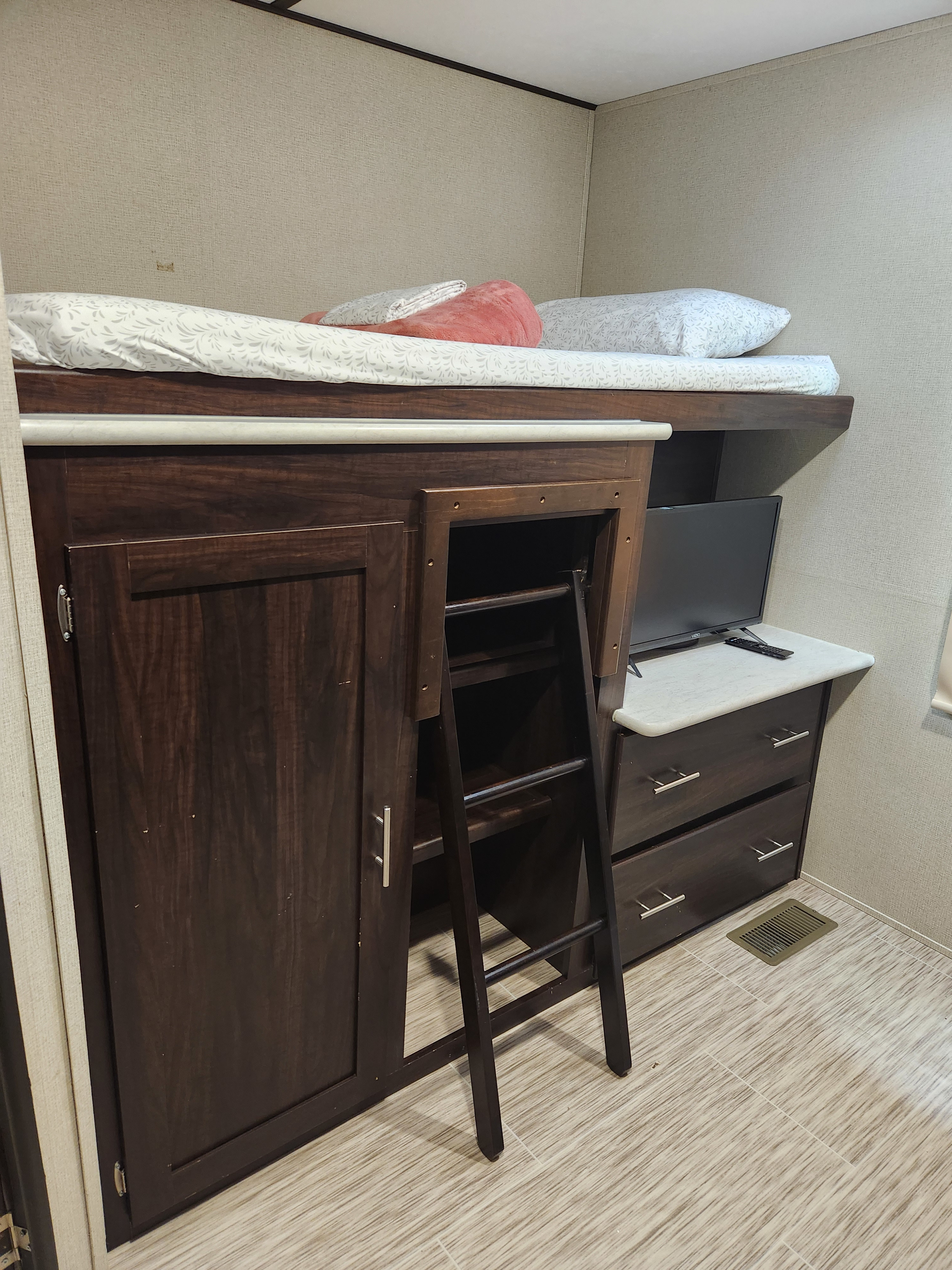 RV rental bunk bed and storage area: a compact sleeping space with a ladder, closet, dresser, and TV for convenience.. Prime Time Lacrosse 2019