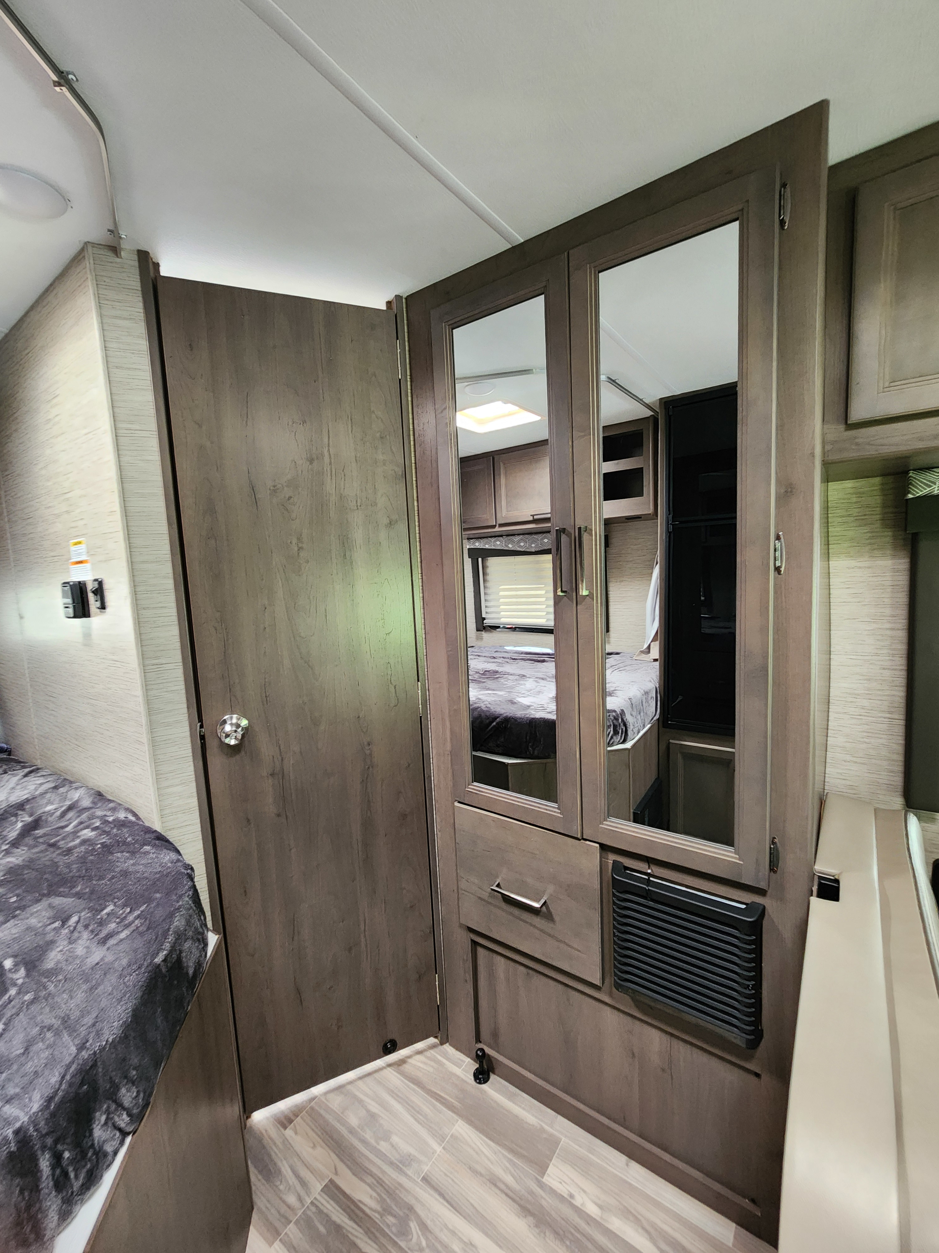 Inside this RV rental: a compact bedroom with a comfy bed, mirrored wardrobe, and practical storage.. Thor Motor Coach Four Winds 2023