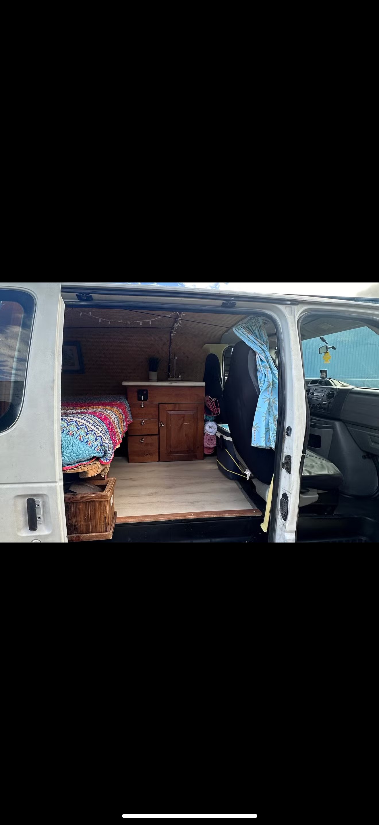Cozy camper van interior for rv rental, featuring a bed, small kitchen, and wooden accents for compact living.. Ford Econoline 150 2010
