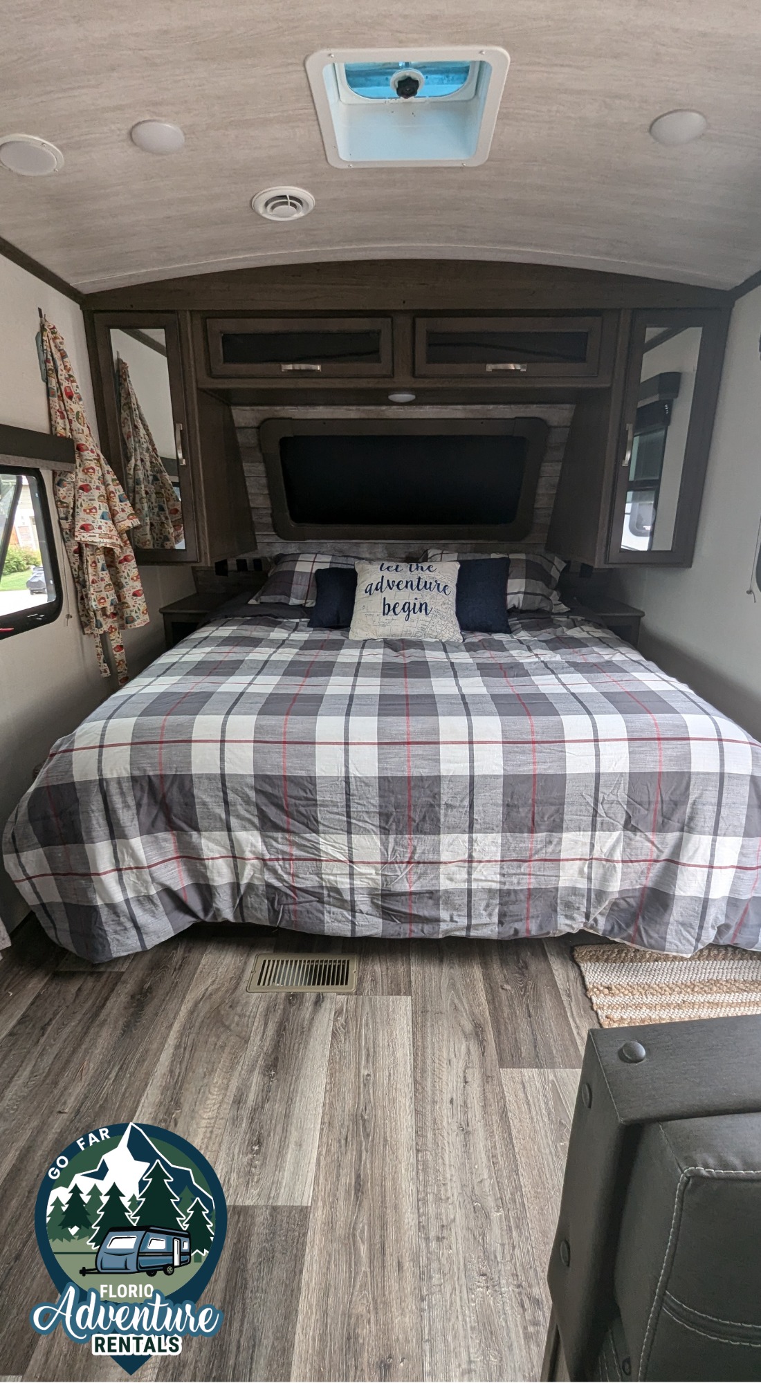 Comfortable RV rental bedroom with plaid bedding, built-in storage, and wood-style flooring.. Keystone RV Cougar 2021