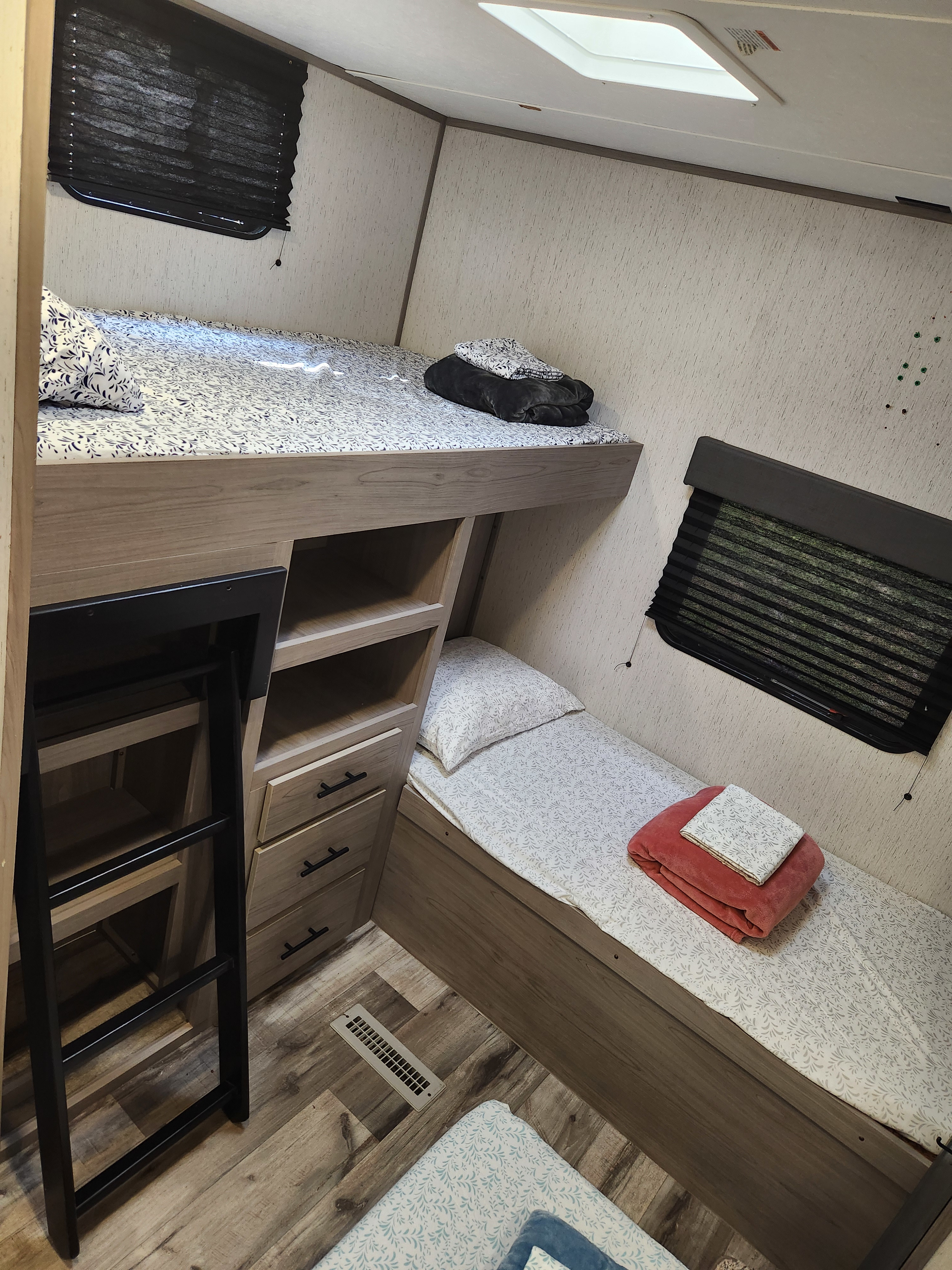 Inside an RV rental: a comfortable bunk area featuring upper & lower beds, built-in storage, and windows with blinds.. Dutchmen Coleman 2022