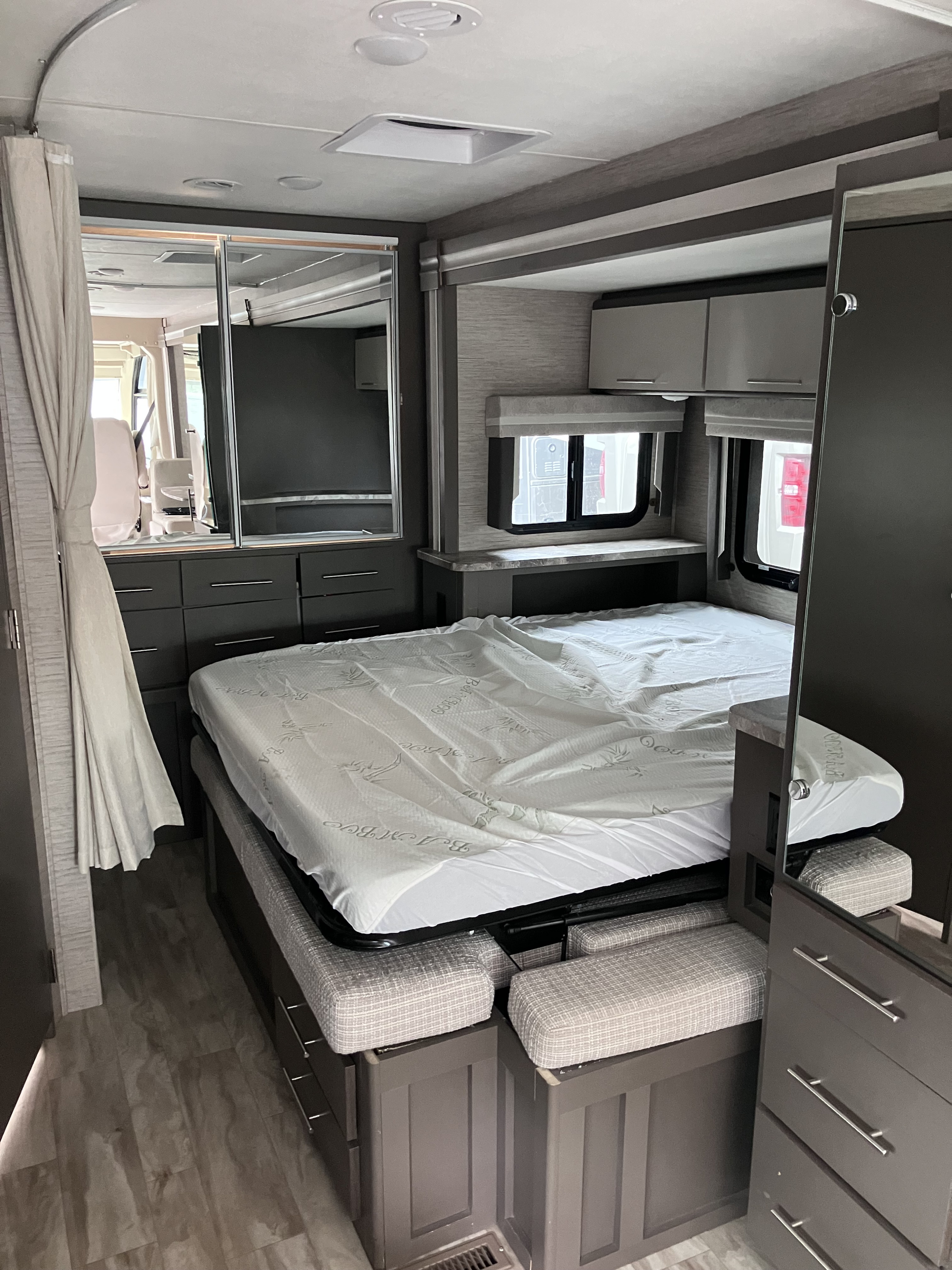 Modern RV rental bedroom with a fold-out bed, overhead cabinets, and mirrored storage for efficient compact living.. Thor Motor Coach Vegas 2022