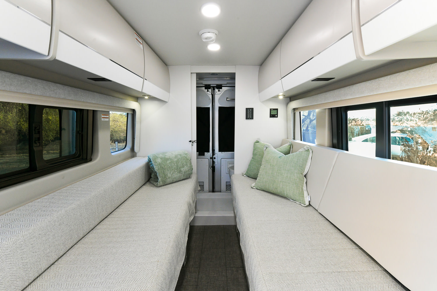 Spacious rv rental interior featuring facing sofas, overhead storage, and large windows for scenic views and comfortable travel.. Entegra Coach Ethos 2024
