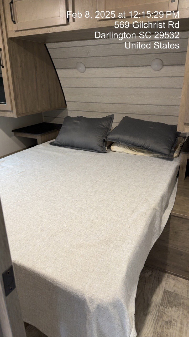 RV rental: Cozy bedroom interior with a neatly made bed, overhead storage, and integrated lighting.. Forest River Puma 2024