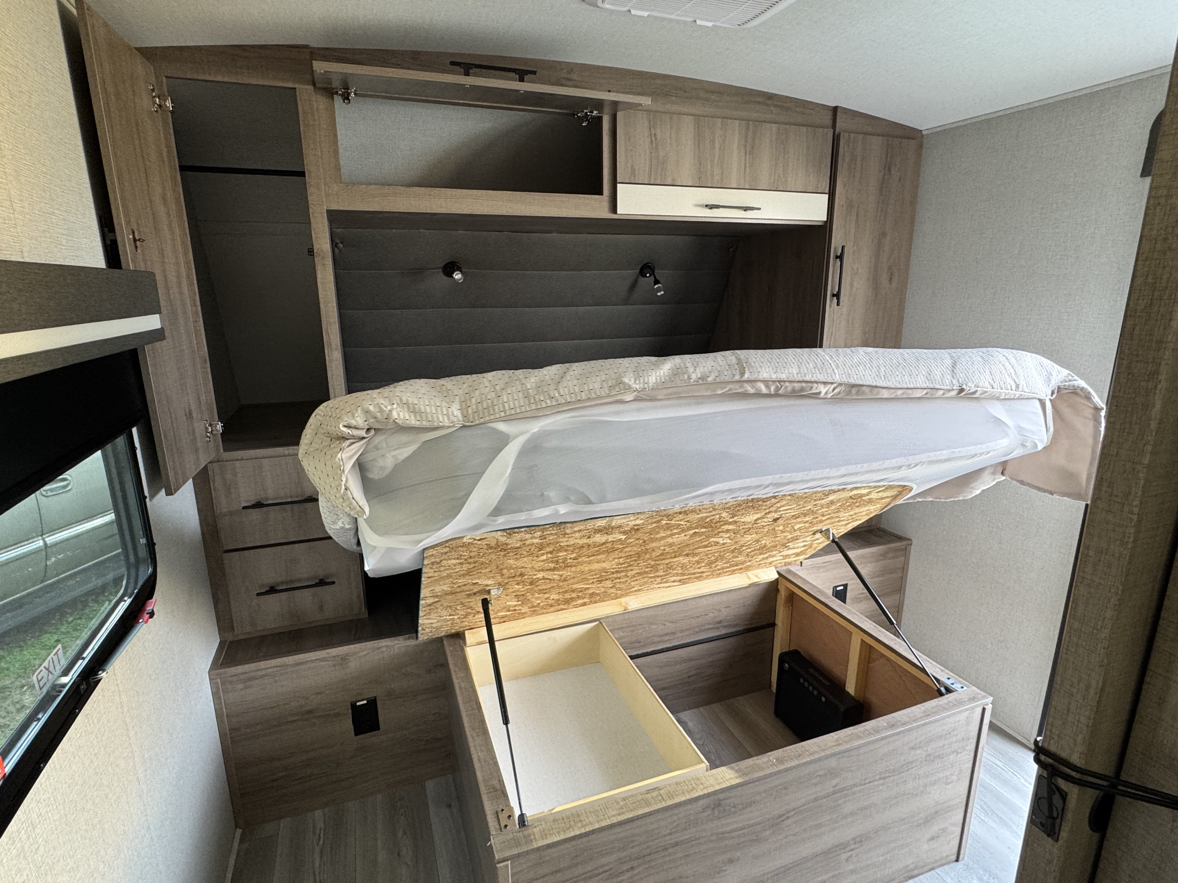 Discover this RV rental's spacious bedroom, featuring a lift-up bed with ample under-storage and functional wall cabinets.. Grand Design Imagine 2024