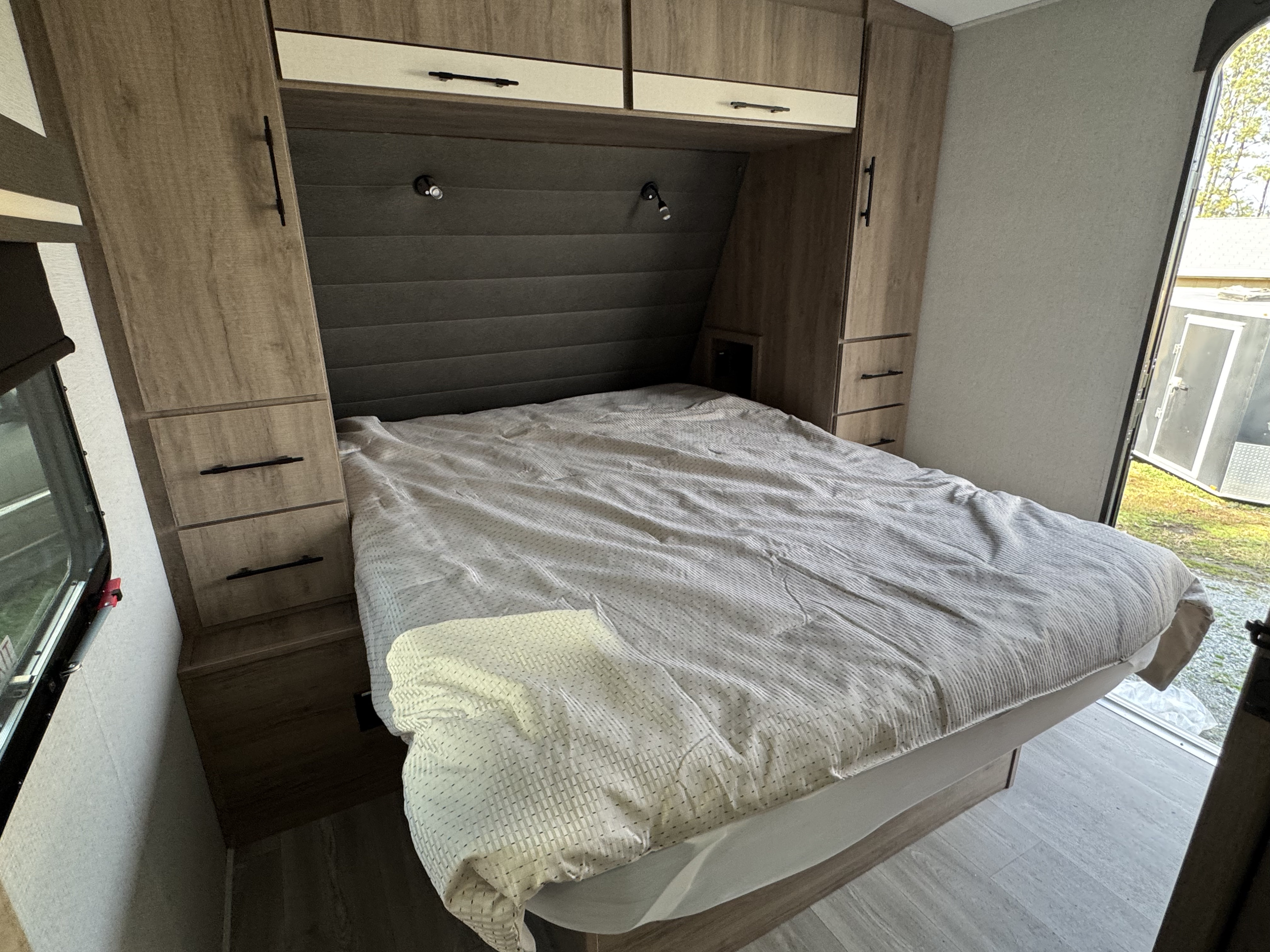 RV rental: Compact bedroom with a comfortable bed, integrated storage cabinets, and a bright outdoor view.. Grand Design Imagine 2024
