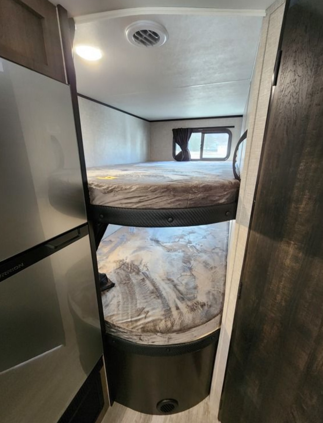 View inside an RV rental showing two stacked bunk beds and a refrigerator. Ideal for family travel.. Jayco Jay Flight 2023