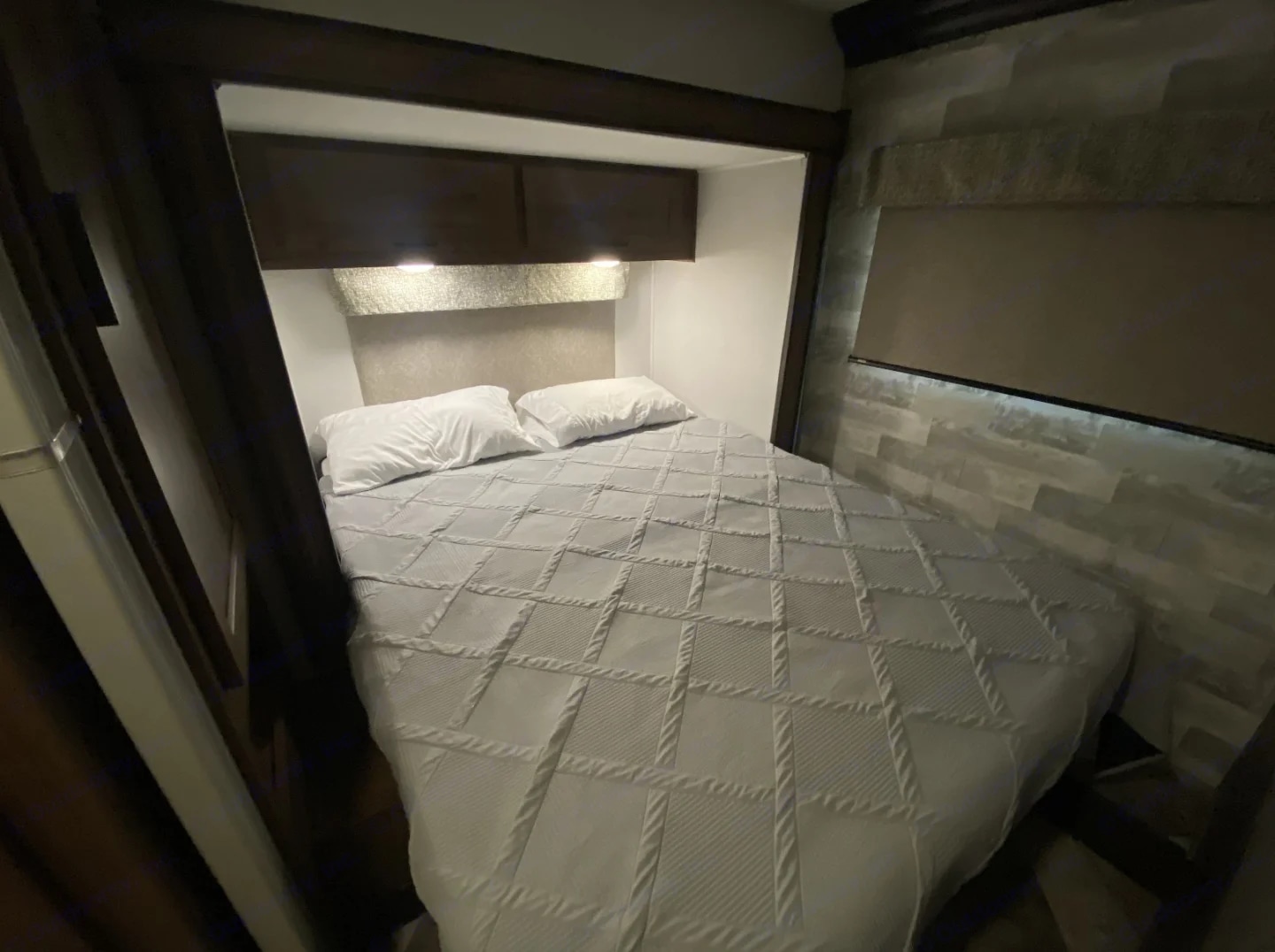 Cozy RV rental bedroom featuring a comfy bed, overhead storage, and ambient lighting, ideal for your travels.. Forest River Forester 2020