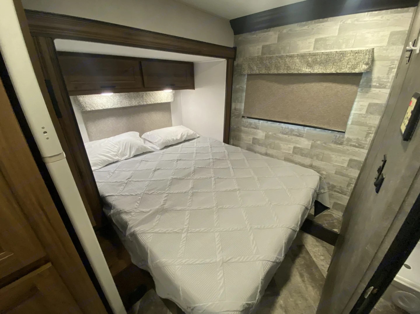 Cozy RV rental bedroom with a comfortable bed, overhead storage, and textured wall, ideal for travel.. Forest River Forester 2020