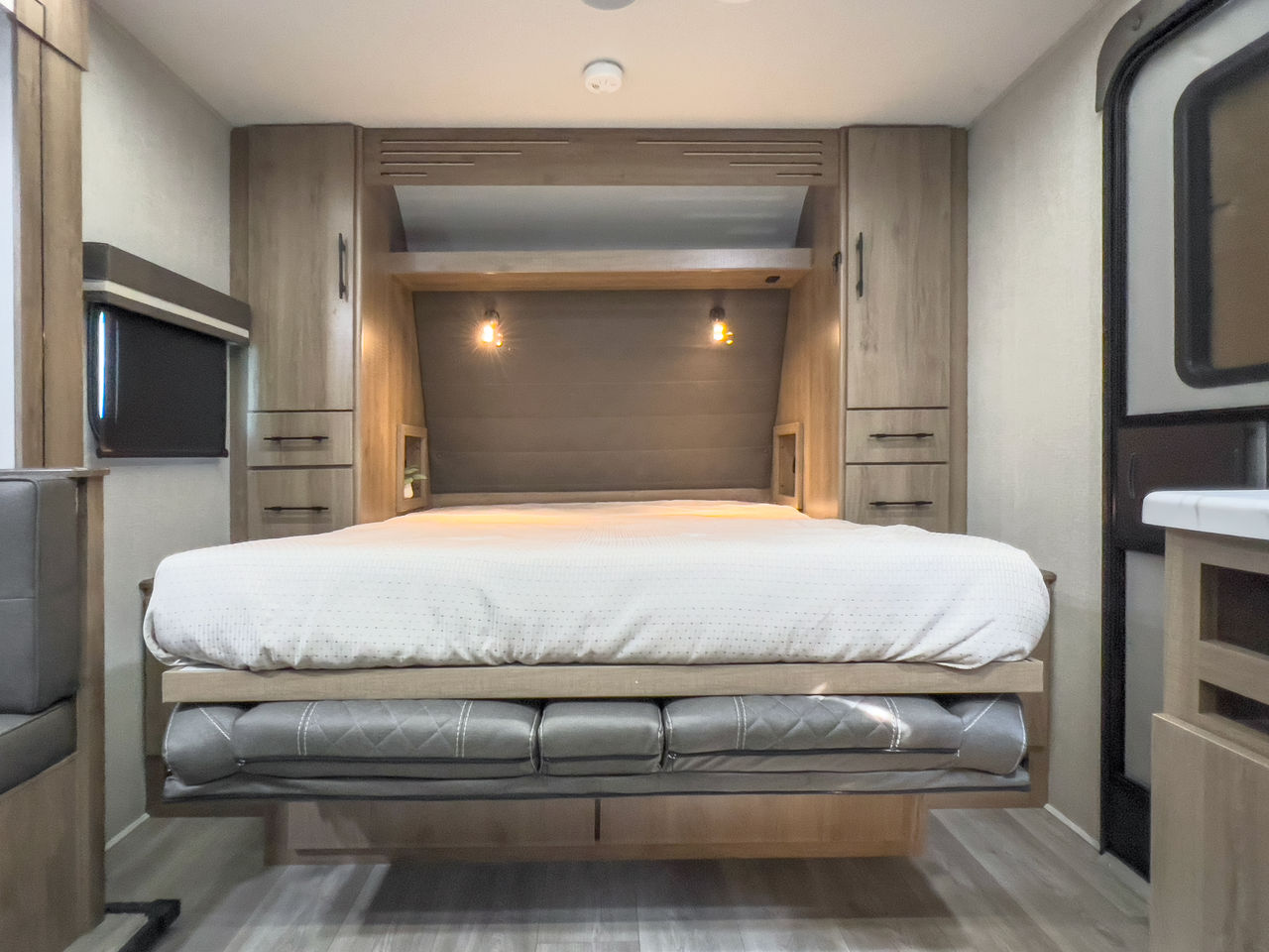 RV rental interior: main bed area with smart storage, cozy lighting, and a convertible lower cushion.. Grand Design Imagine XLS 2024