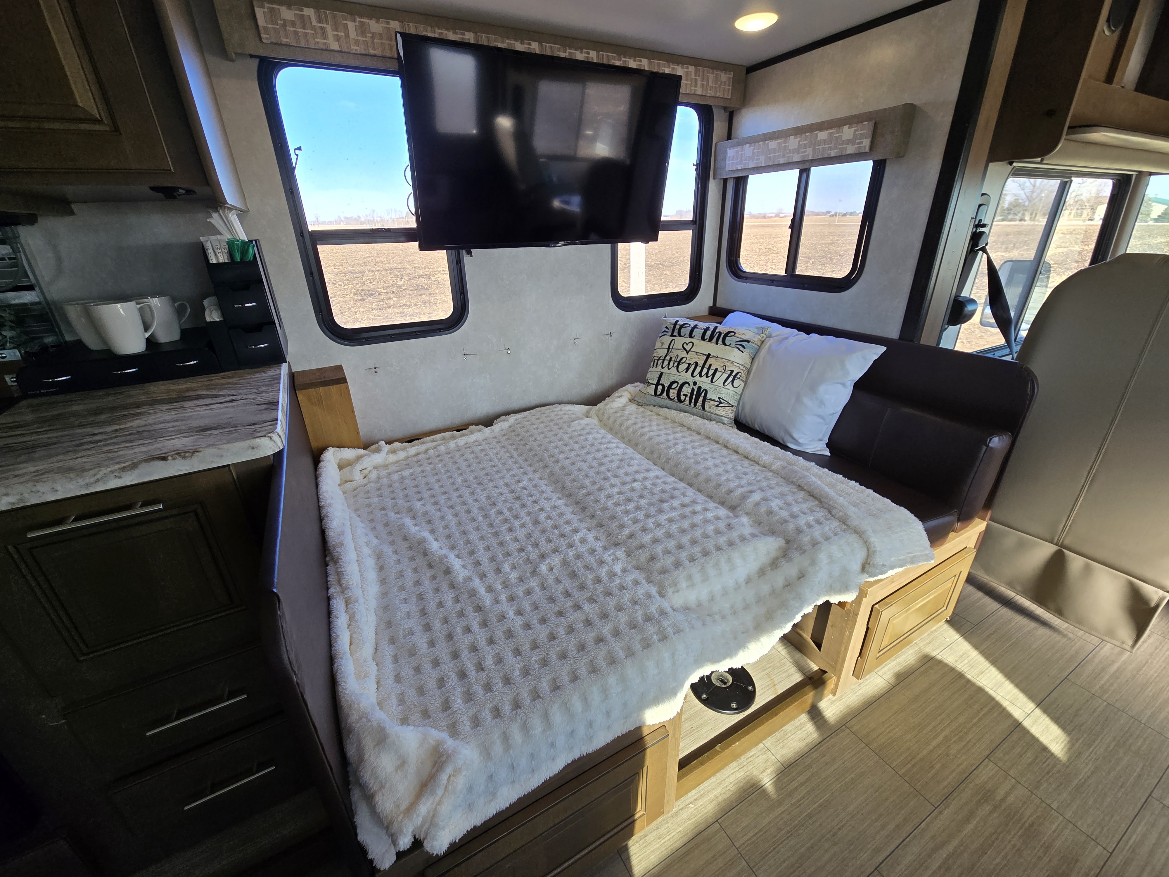Cozy RV rental interior featuring a dinette converted to a bed, kitchen counter, and scenic field views through windows.. FR3 FR3 Motorhome 2021