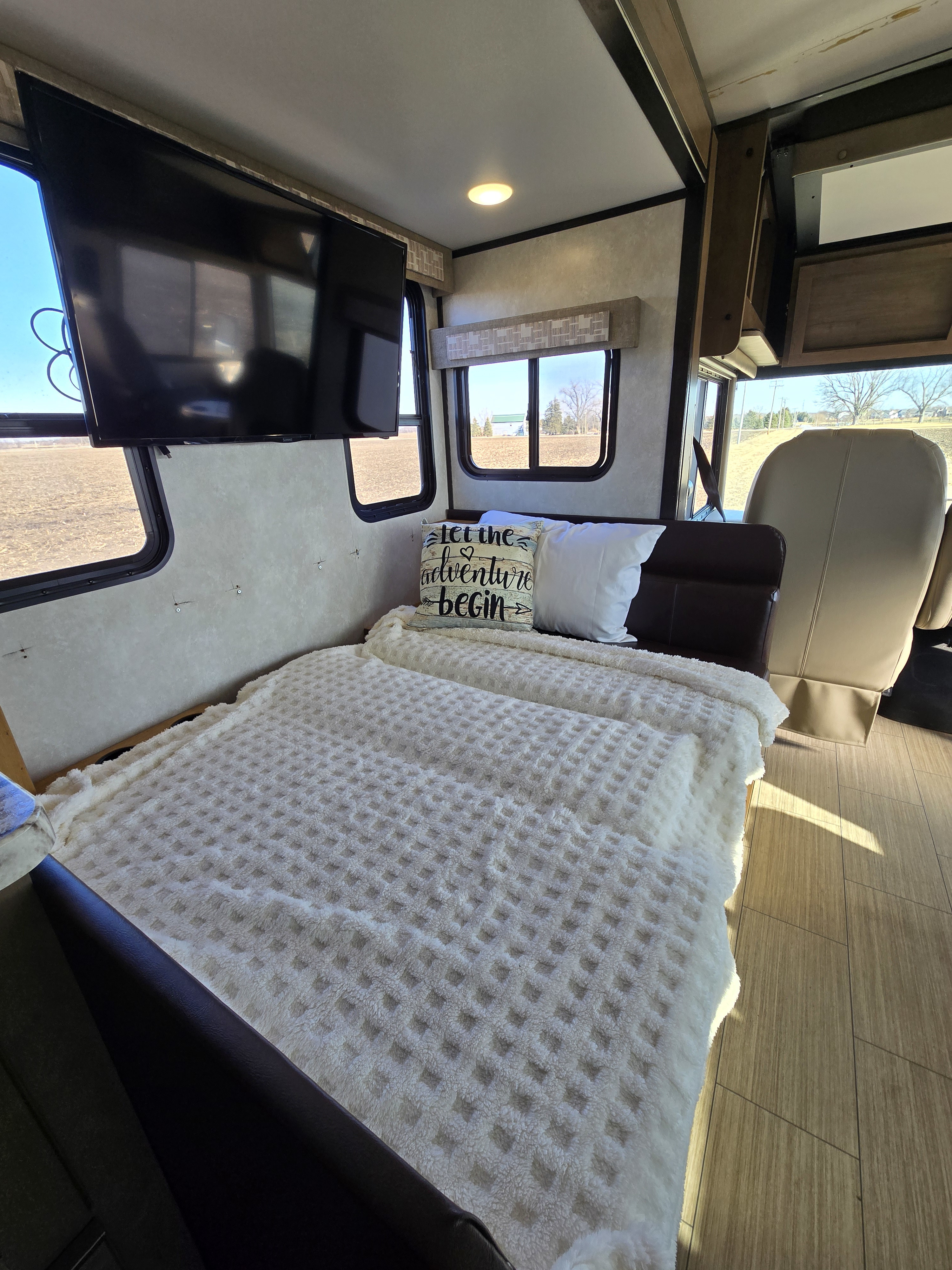 Comfortable RV rental interior featuring a cozy bed, mounted TV, and expansive windows with scenic views.. FR3 FR3 Motorhome 2021