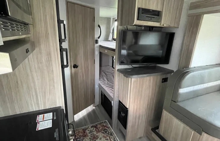 Explore this inviting rv rental interior, featuring a kitchen, bunk beds, TV entertainment, and a comfortable dinette.. Winnebago Micro Mini 2306BHS 2019