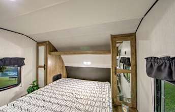 Spacious RV rental bedroom with a comfy bed, side cabinets, and windows, perfect for travel. This camper interior offers cozy sleeping.. Heartland RVs Pioneer 2021