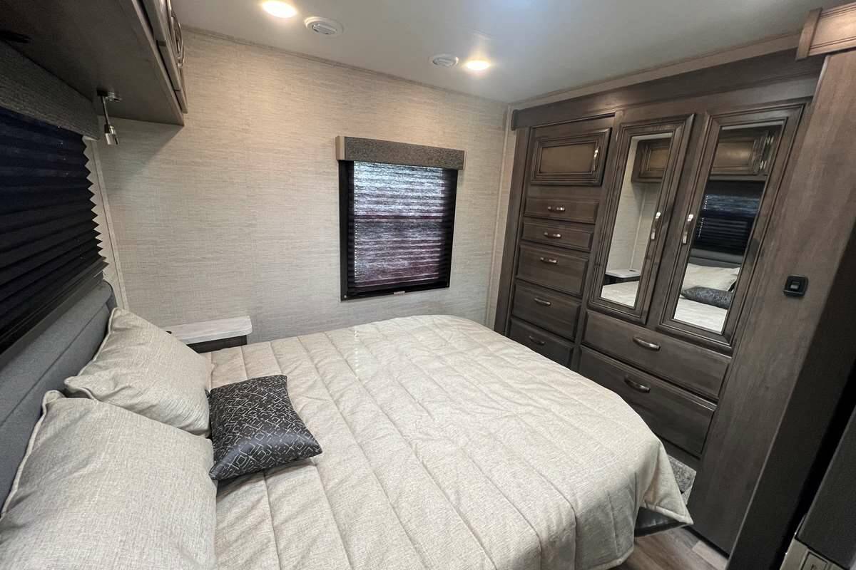 Comfortable RV rental bedroom featuring a full bed, built-in mirrored wardrobe, and a window for cozy travels.. Jayco Redhawk 2023