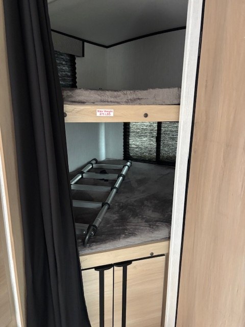 RV rental interior with cozy bunk beds and ladder. Upper bed features a 275 lbs max weight limit. Compact storage below.. Cruiser Rv Corp Radiance 2022