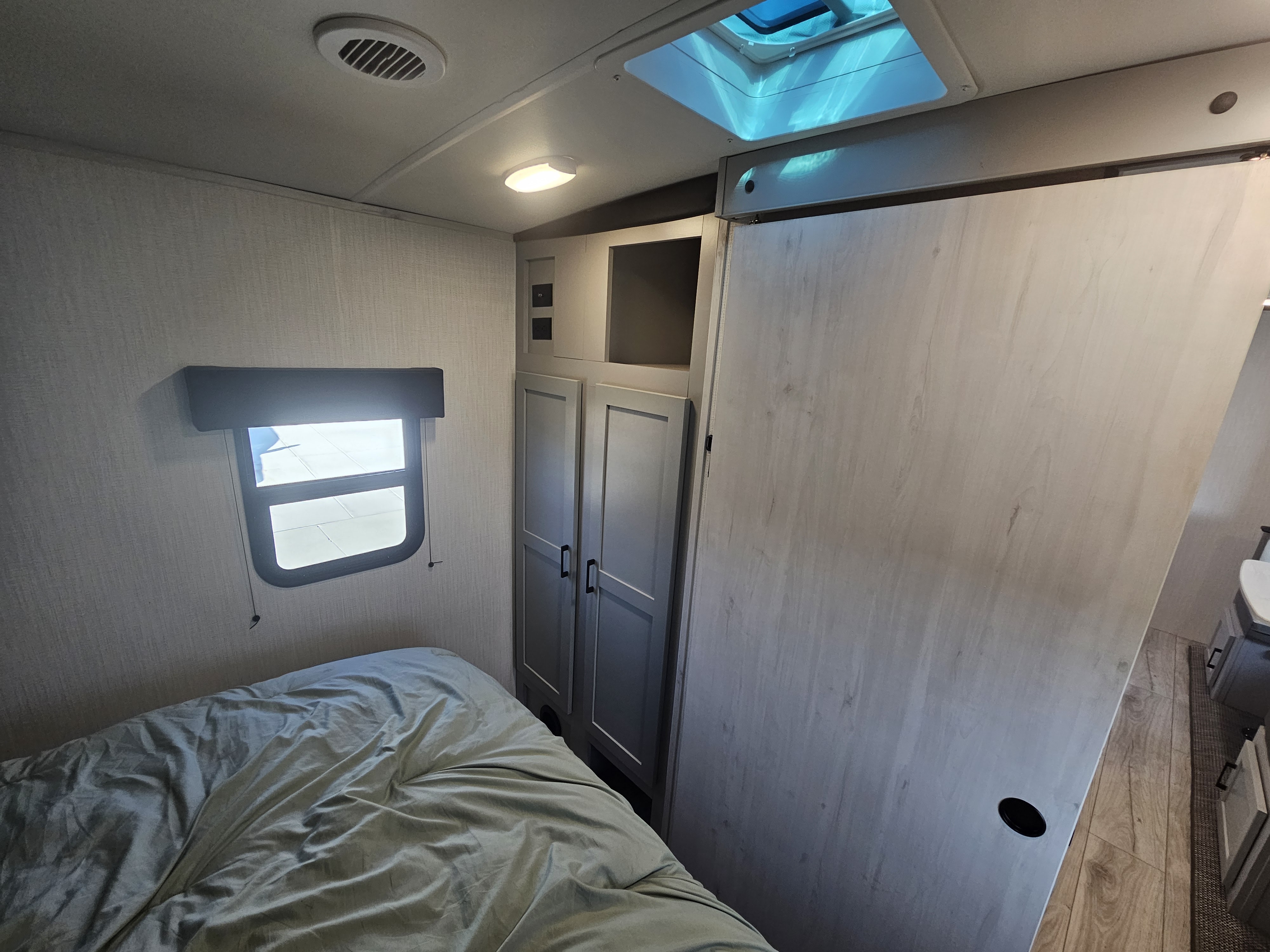 RV rental bedroom: cozy space with bed, window, built-in storage, sliding door, and skylight.. Heartland RVs North Trail 2024