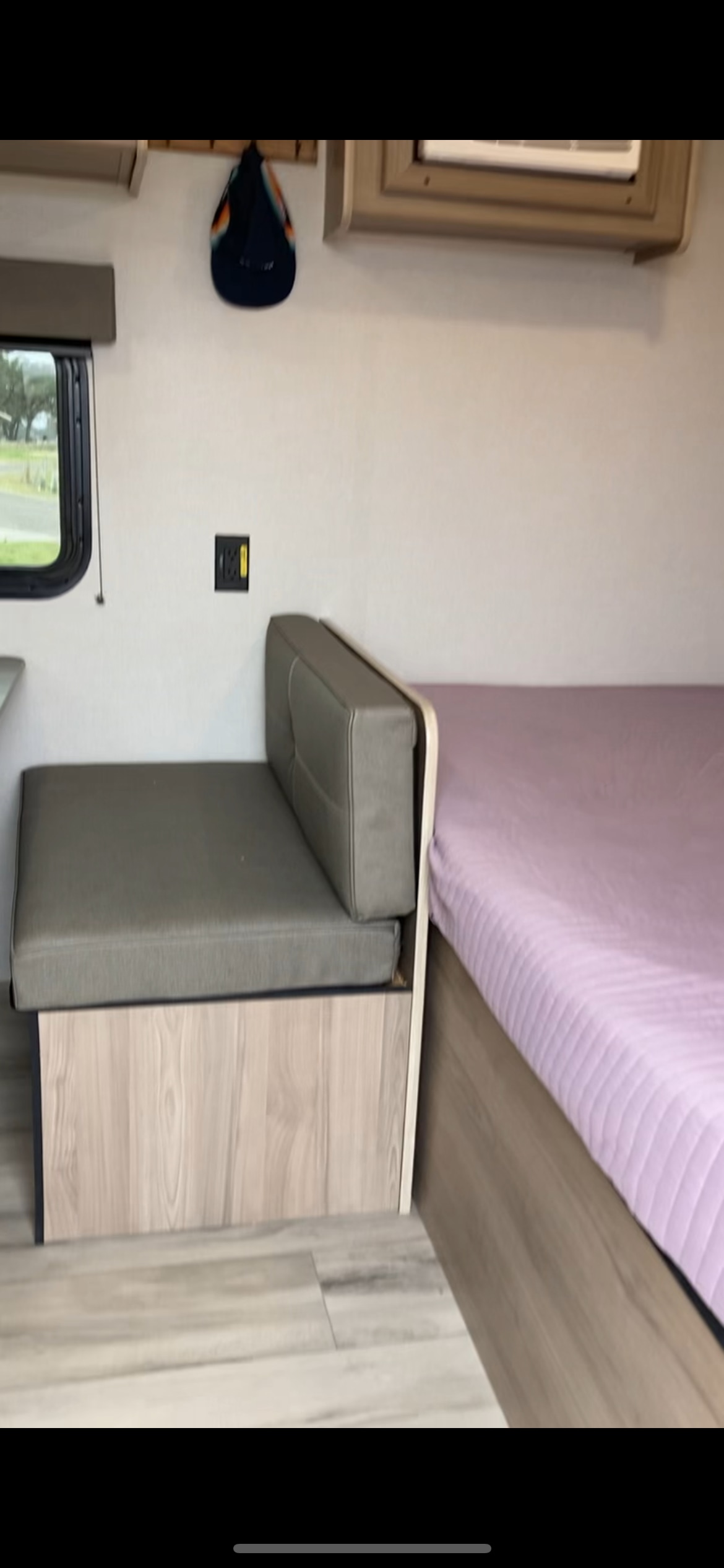Inside an RV rental: a compact interior with a gray cushioned bench, a bed, and a window for scenic views.. 4YDTCMG17SM936605 17B 2025