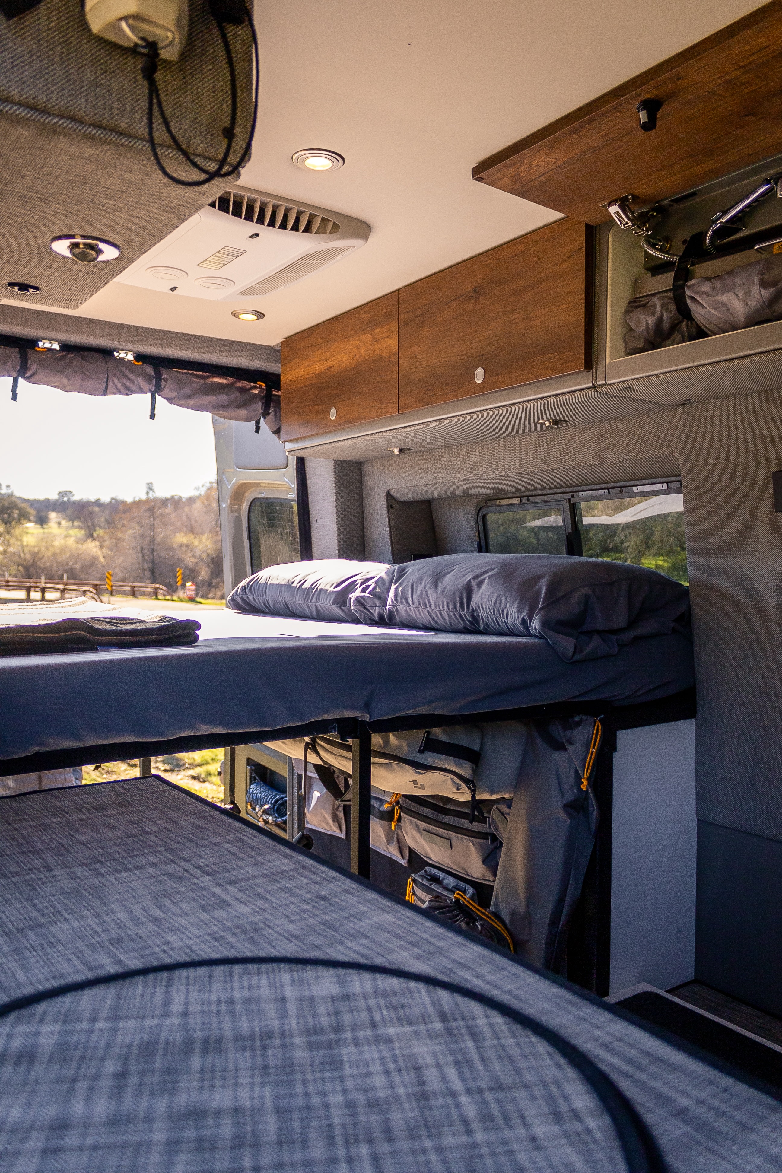 Spacious RV rental interior with bunk beds, overhead storage, and scenic views, ideal for travel and camping.. Storyteller Overland Beast MODE 2024