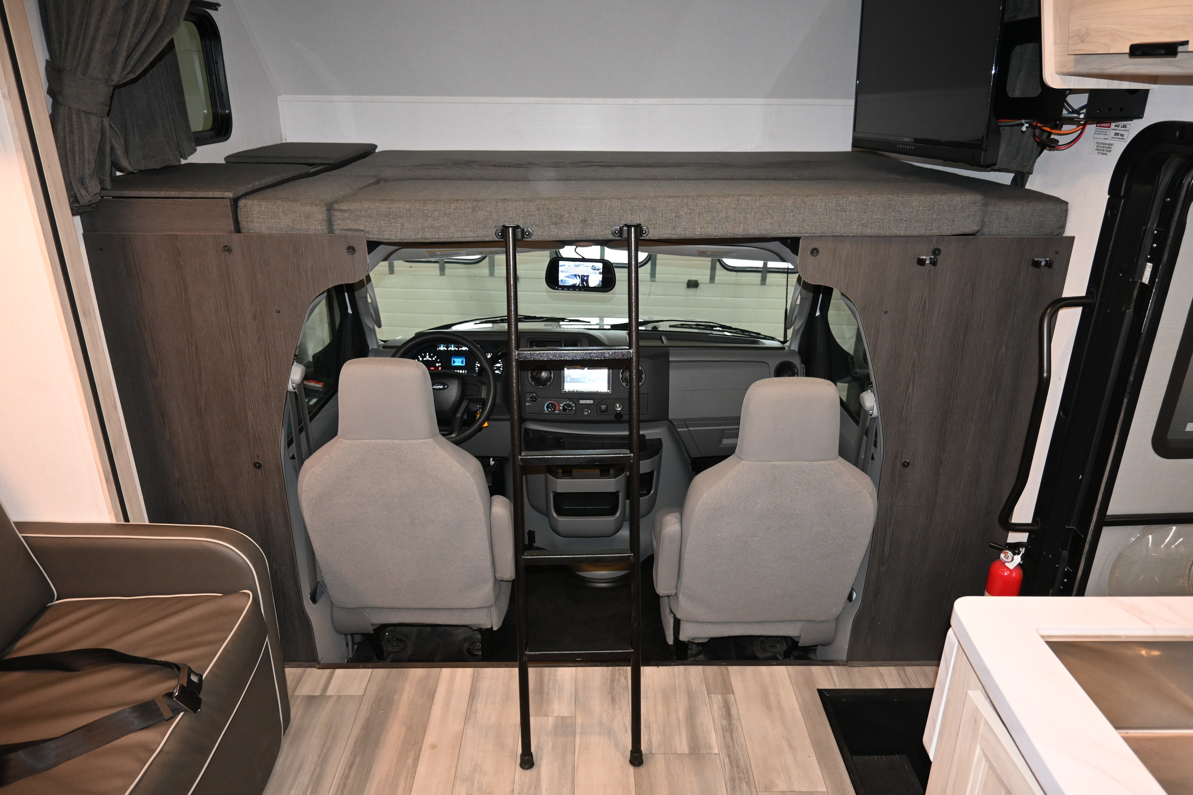 An RV rental interior with a built-in overhead bed, ladder access, and the vehicle's cockpit visible.. Forest River Sunseeker - LE Series M-2850S 2024